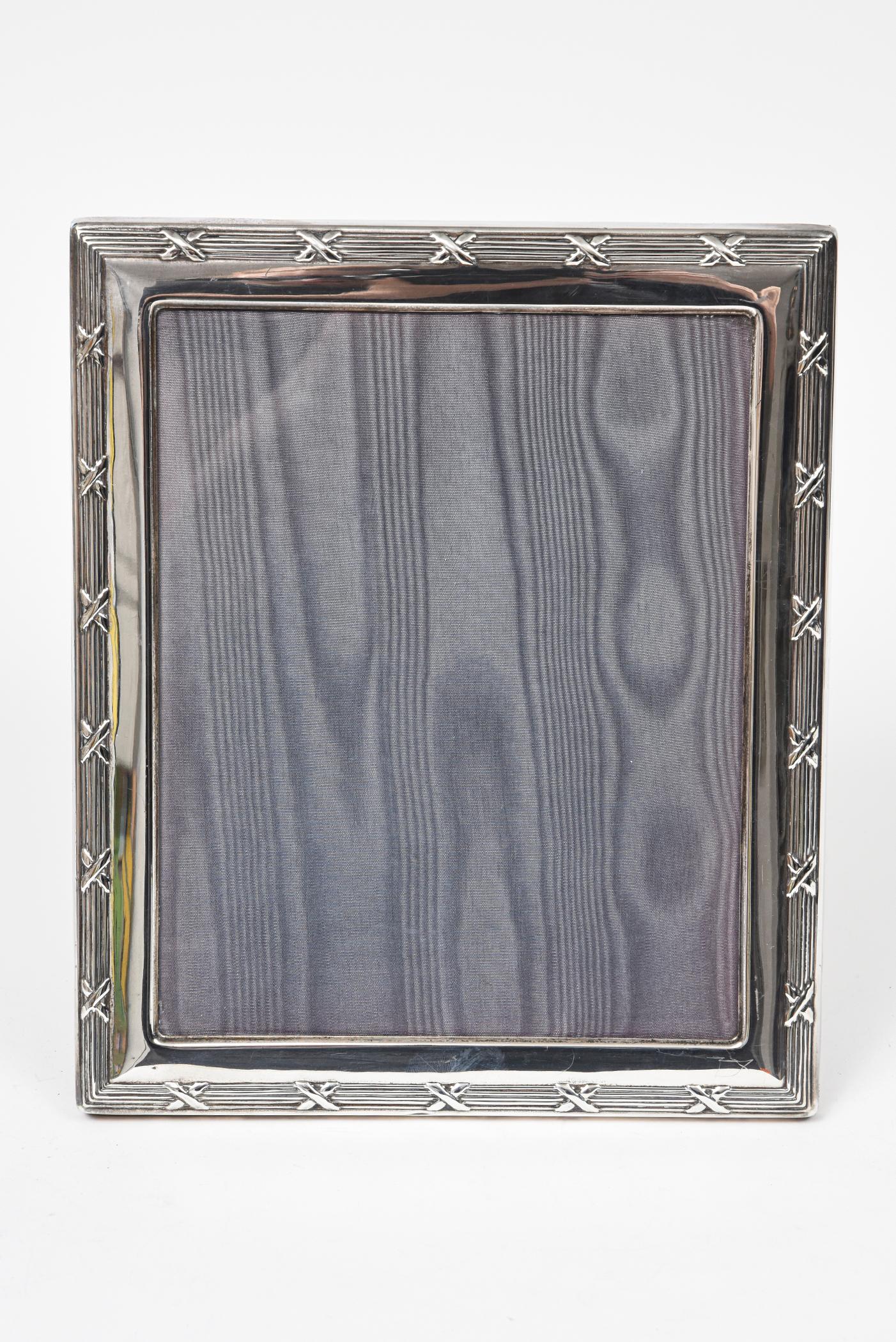 Rectangular sterling silver picture frame featuring a reed & ribbon raised motif by R. Carr Ltd. The Carrs of Sheffield made this frame in 1994. The frame is a classic design and showcases the family-run brand's silversmith skills. Finished with a