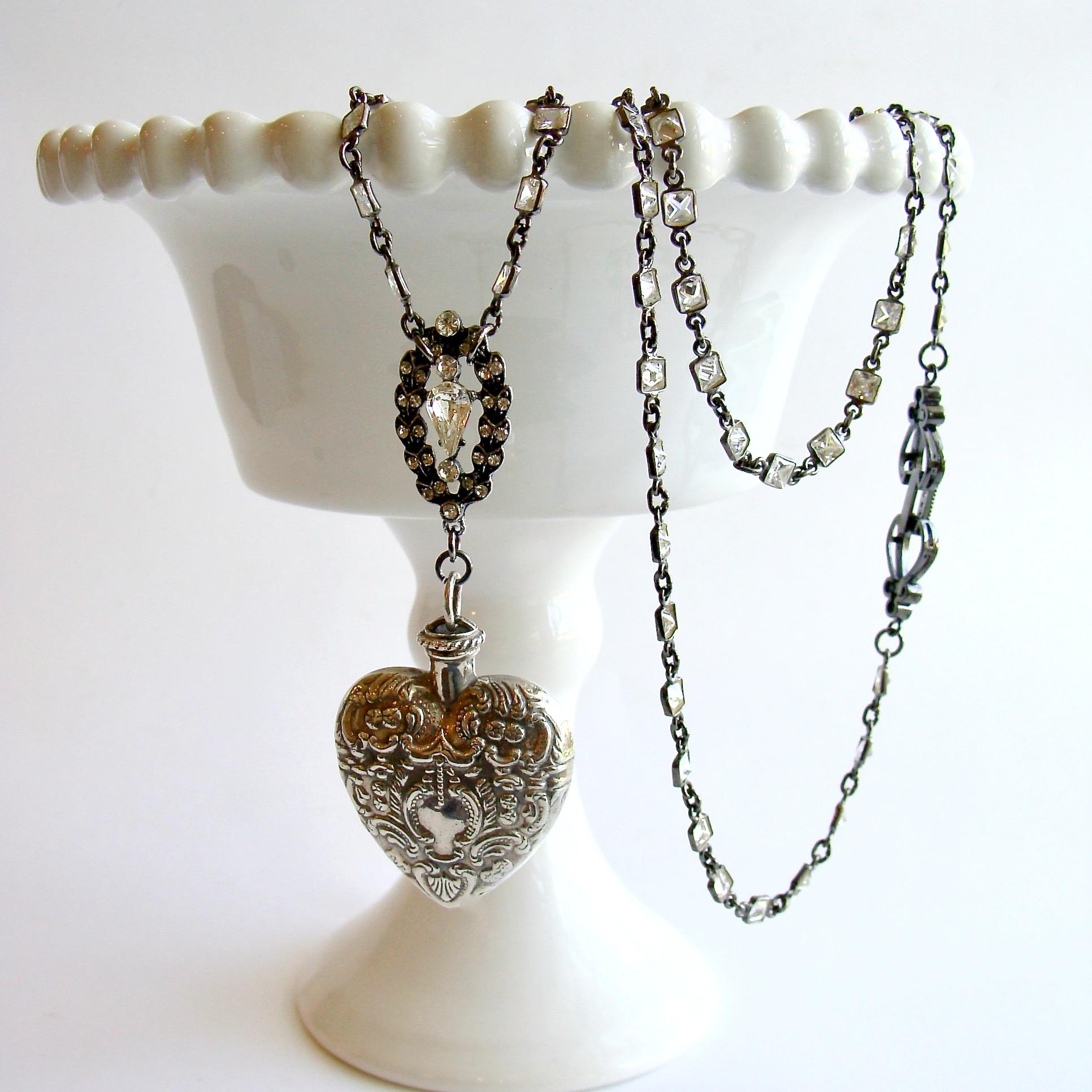 A lovely antique sterling silver repousse chatelaine heart scent bottle is the focal point of this beautiful layering necklace.  A charming rhodium silver paste cartouche presides over the top of this feminine heart shaped bottle, while a sparkling