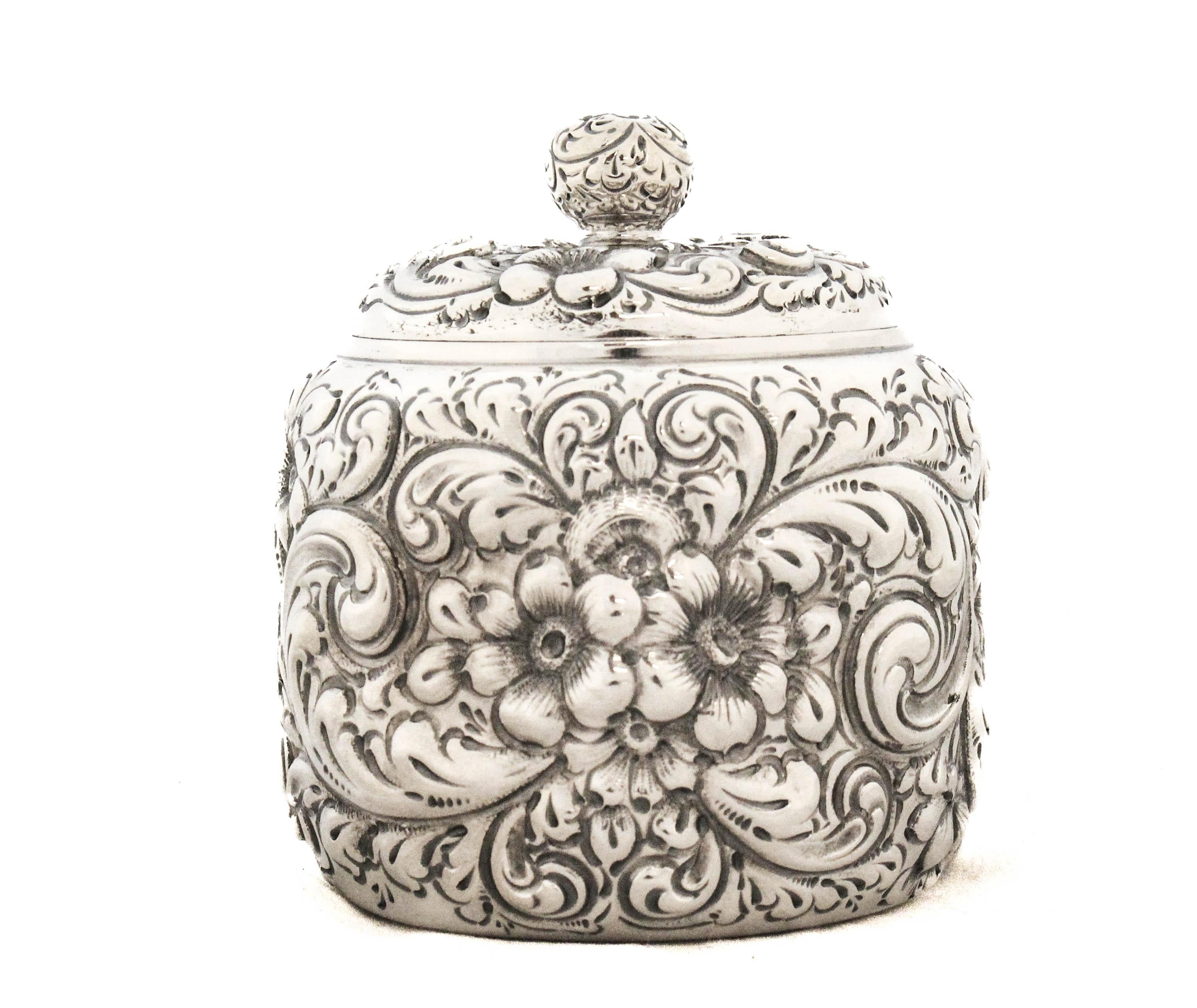 This exquisite sterling silver lidded jar showcases masterful craftsmanship and ornate detailing throughout. The entire surface is richly decorated in repoussé and chased floral and scroll motifs, creating a stunning three-dimensional texture that