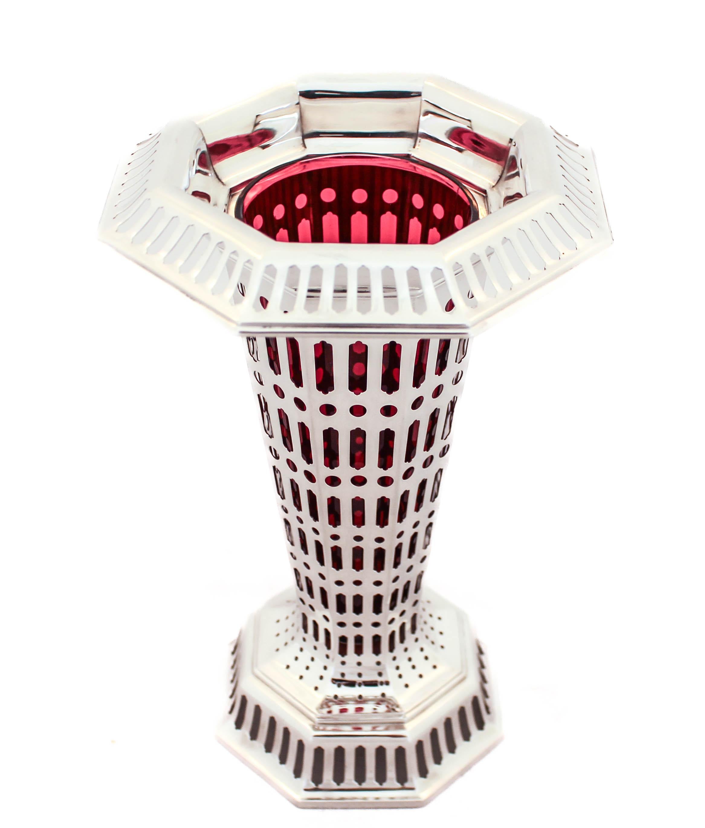 Being offered is a sterling silver vase by the world renowned Tiffany and Company.  It has a reticulated design with a ruby-red glass liner.  The glass insert is removable so it’s easy to wash and replace.  The cutout design is geometric and allows