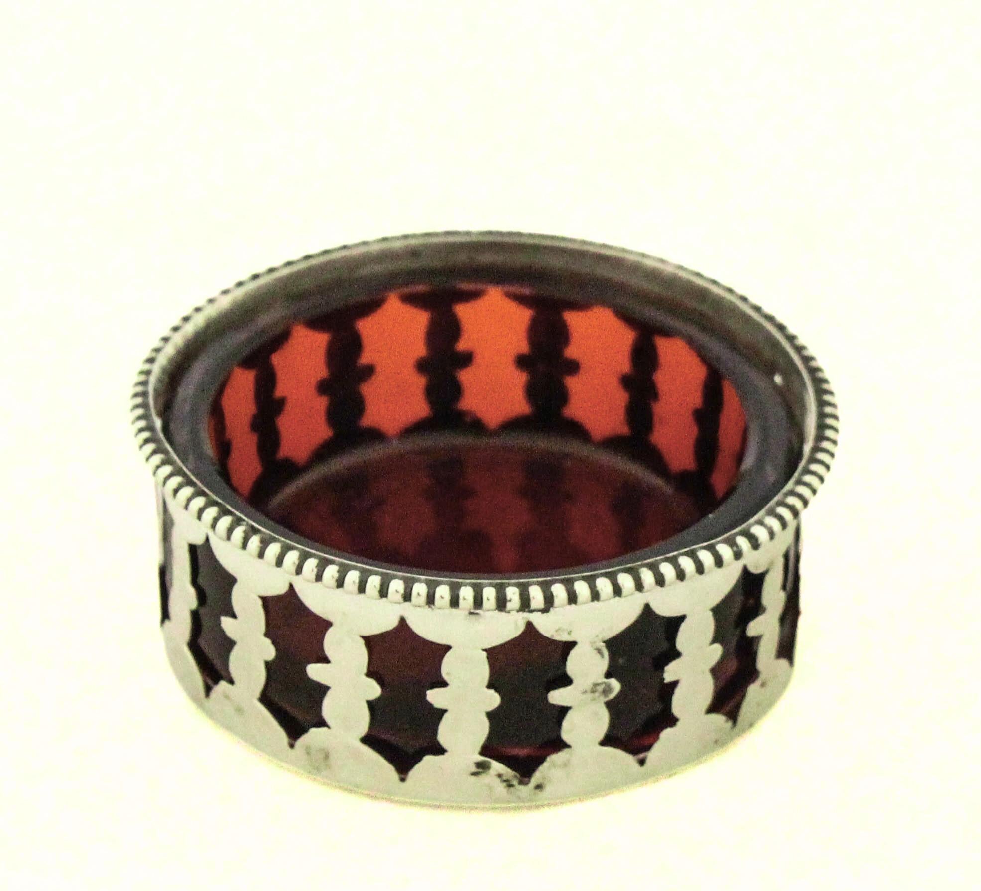Ein charmanter, offener Salzstreuer aus Sterlingsilber mit einem herausnehmbaren, rubinroten Glaseinsatz. Das Stück ist ein Beispiel für das raffinierte Geschirr der frühen 1900er Jahre, das Funktionalität mit eleganten dekorativen Details