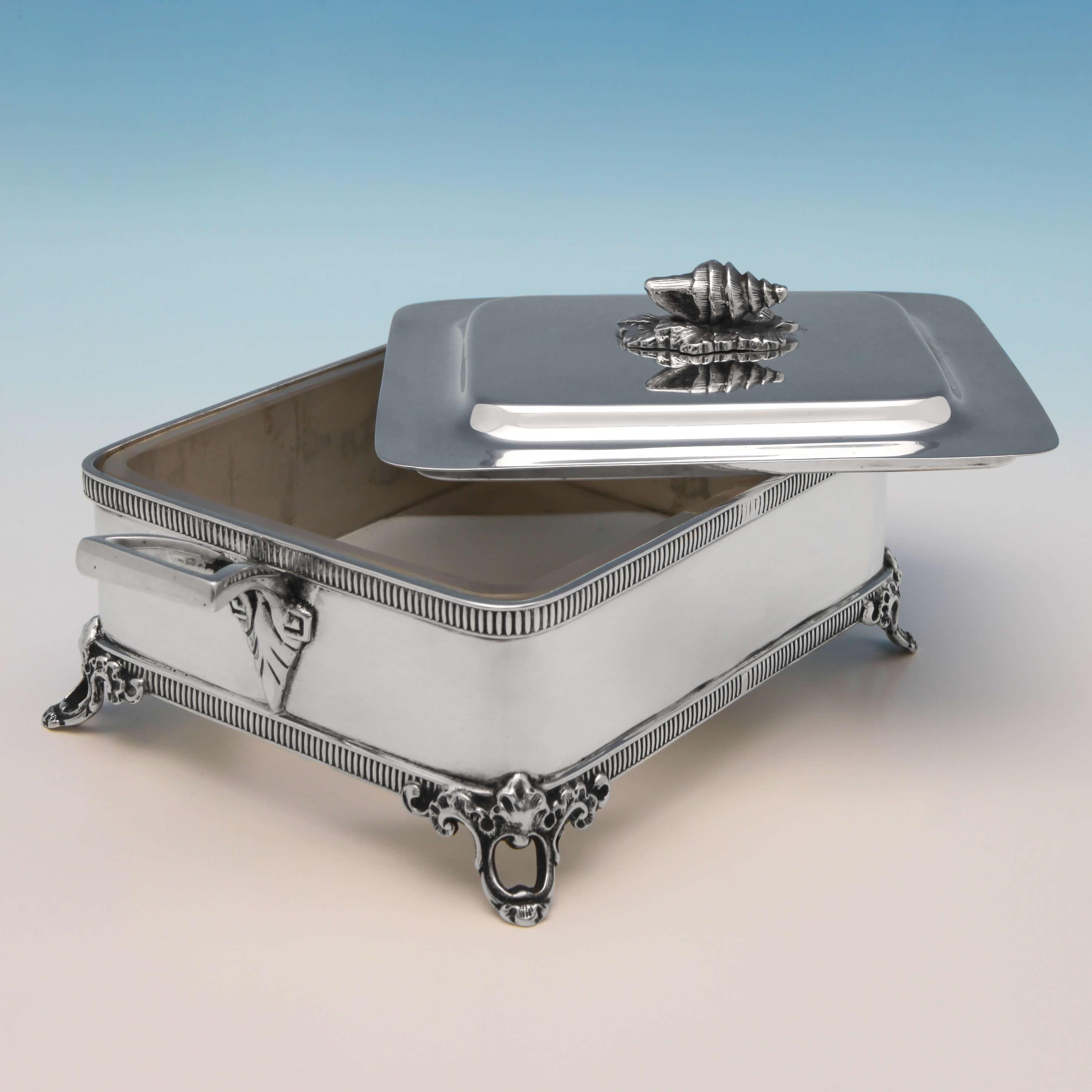 Hallmarked in Sheffield in 1908 by Walker & Hall, this attractive, Edwardian, antique sterling silver Sardine dish, features egg and dart borders, applied feet, a conch shell finial and a frosted, glass liner. The sardine dish measures 3.5