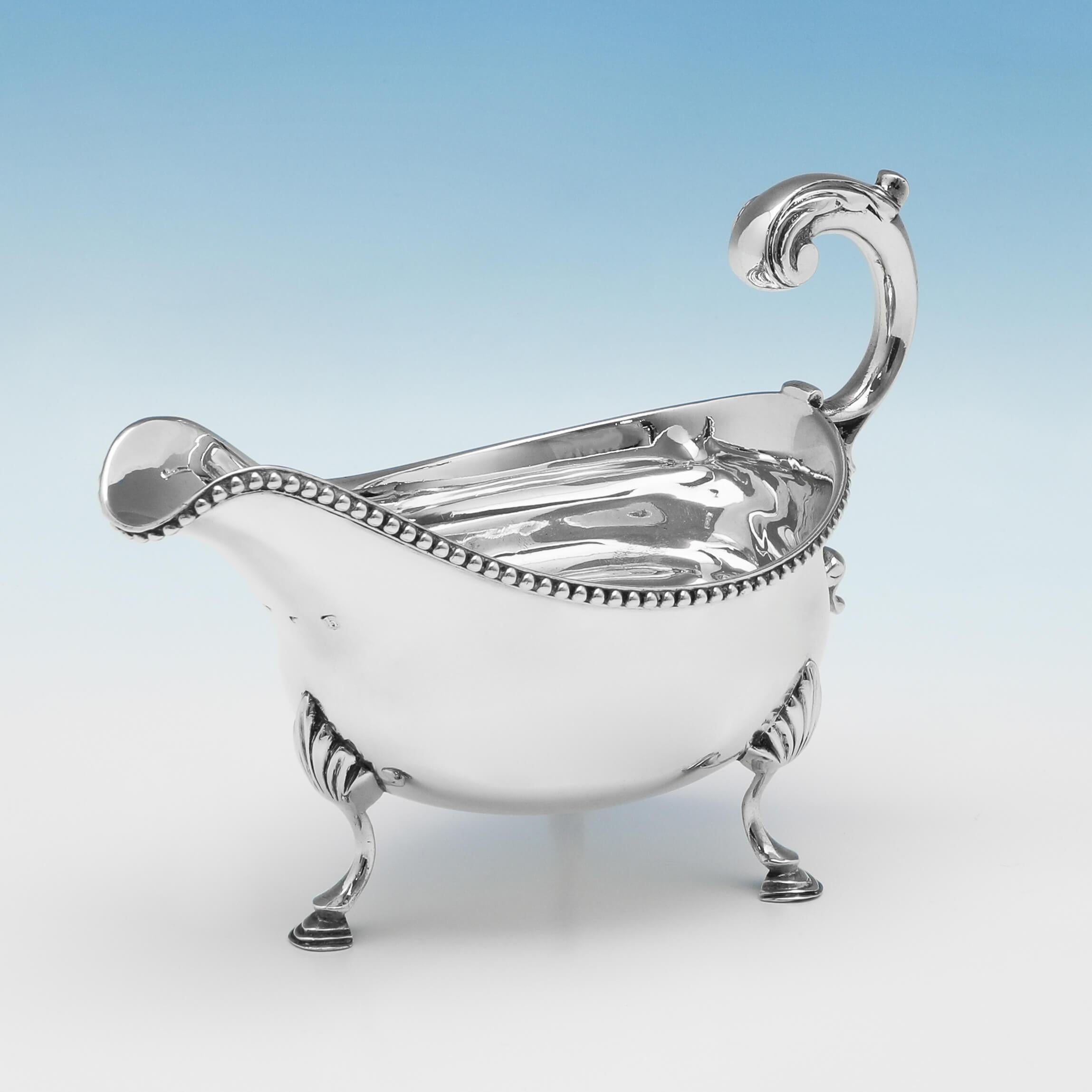 Hallmarked in London in 1783, this George III, antique sterling silver sauce boat, features a bead border, an acanthus detailed handle, and stands on three hoof feet. The sauce boat measures 4.75