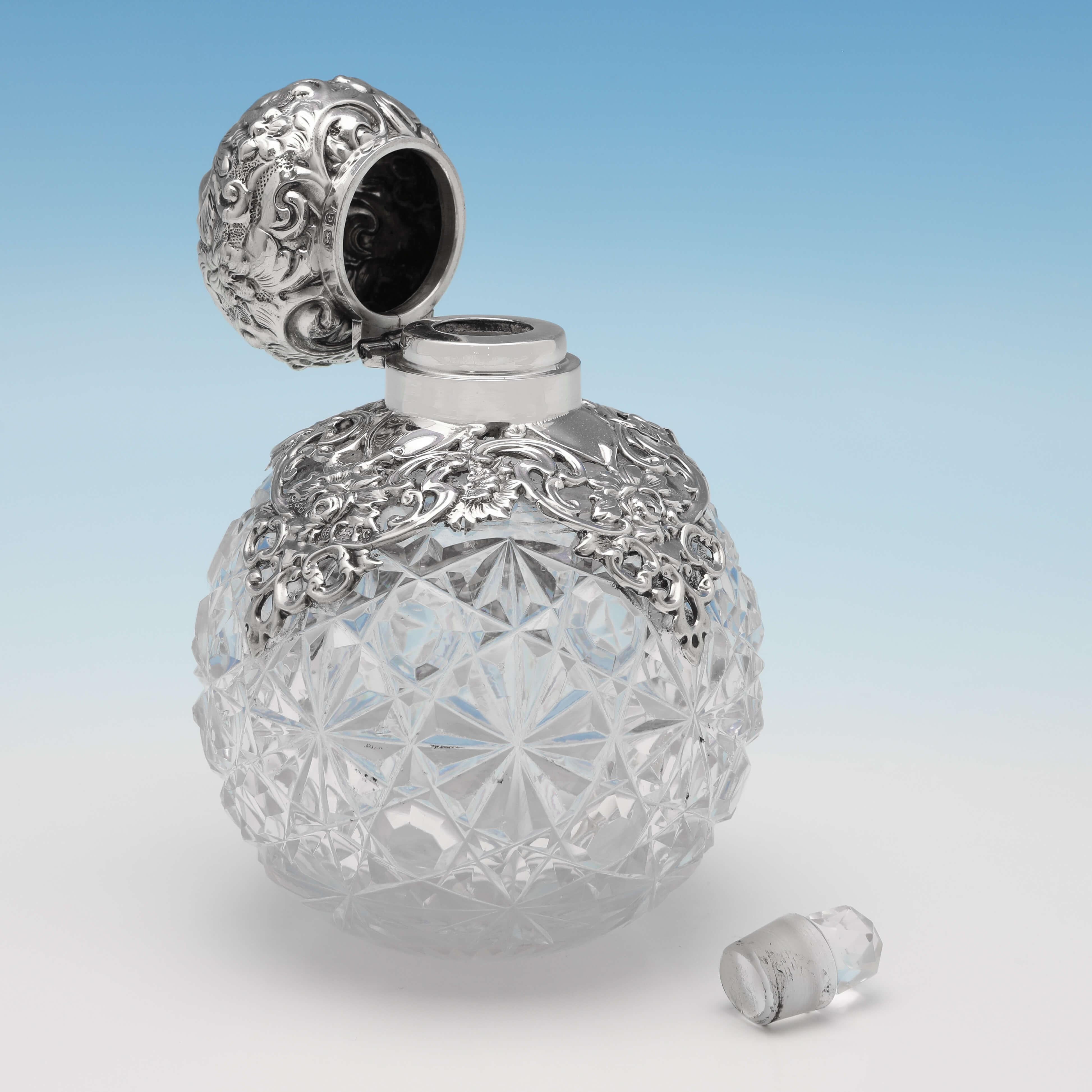 Hallmarked in Birmingham in 1902 by Synyer & Beddoes, this attractive, Antique Sterling Silver Scent Bottle, features an ornate silver lid and mount, and a cut glass body. The scent bottle measures 4.5
