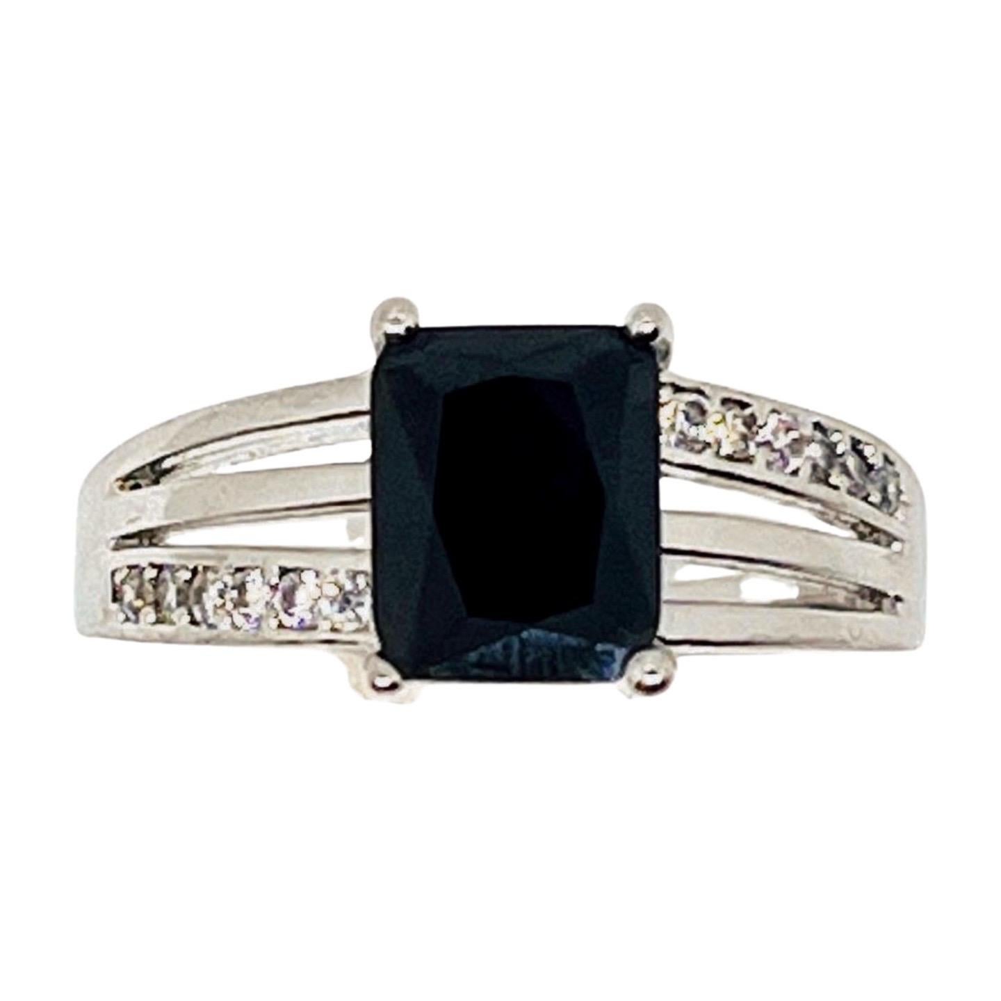 Hematite ring, 925 Silver, marked, scissor-cut rectangular stone, Channel-set 12 small, clear, square-cut cubic zirconias channel set on split shoulders. Raised band, simple profile, stone set in open-back fancy basket setting. Made 2000s.

This is