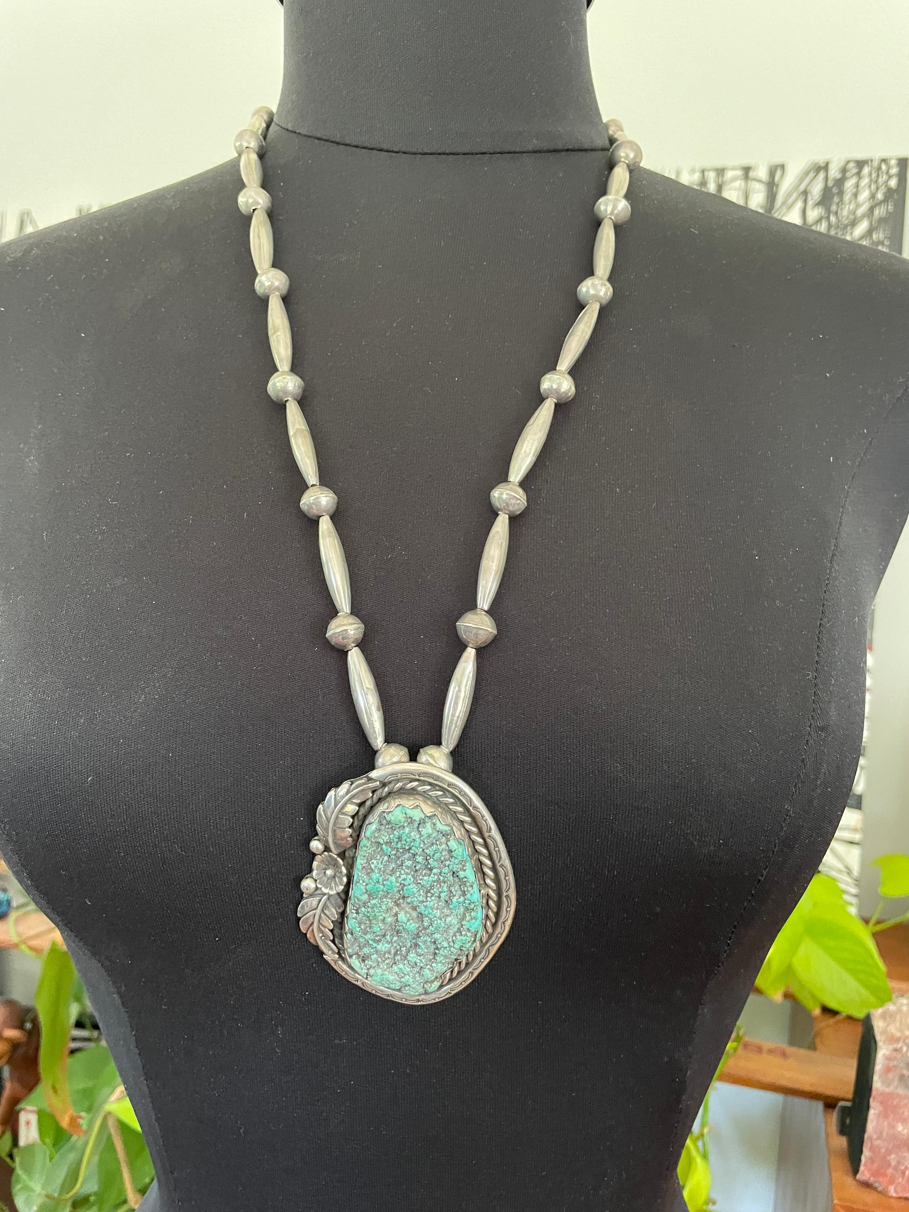 Un enorme turchese naturale con schiuma di mare incastonato in un'elegante montatura in argento sterling. Motivo piumato  Si tratta di un pezzo di turchese blu-verde con marchio di garanzia sul retro. La catena è di perline in sterling ed è