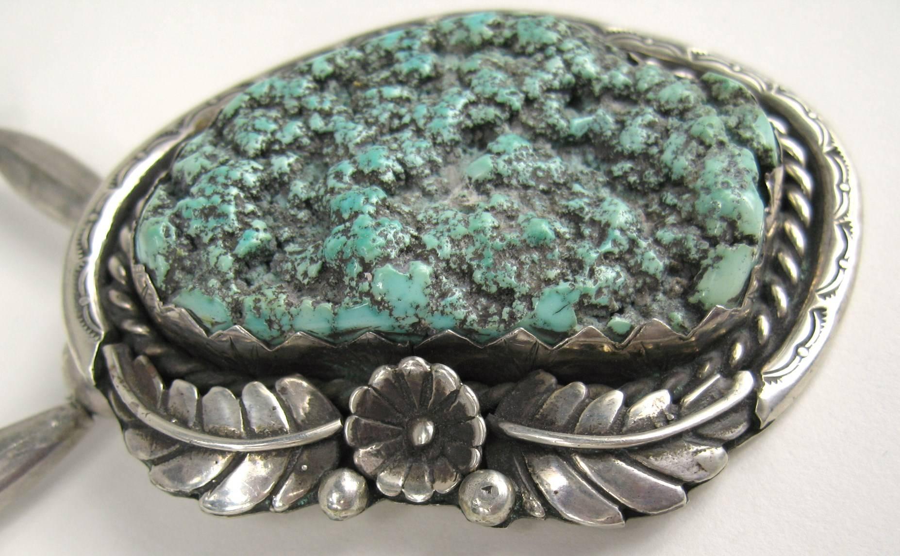 Une énorme turquoise naturelle en forme d'écume de mer est sertie dans une monture ornée en argent sterling. Motif plumes  Il s'agit d'un morceau de turquoise bleu-vert bouillonnant, poinçonné au dos. La chaîne est en sterling perlé et est