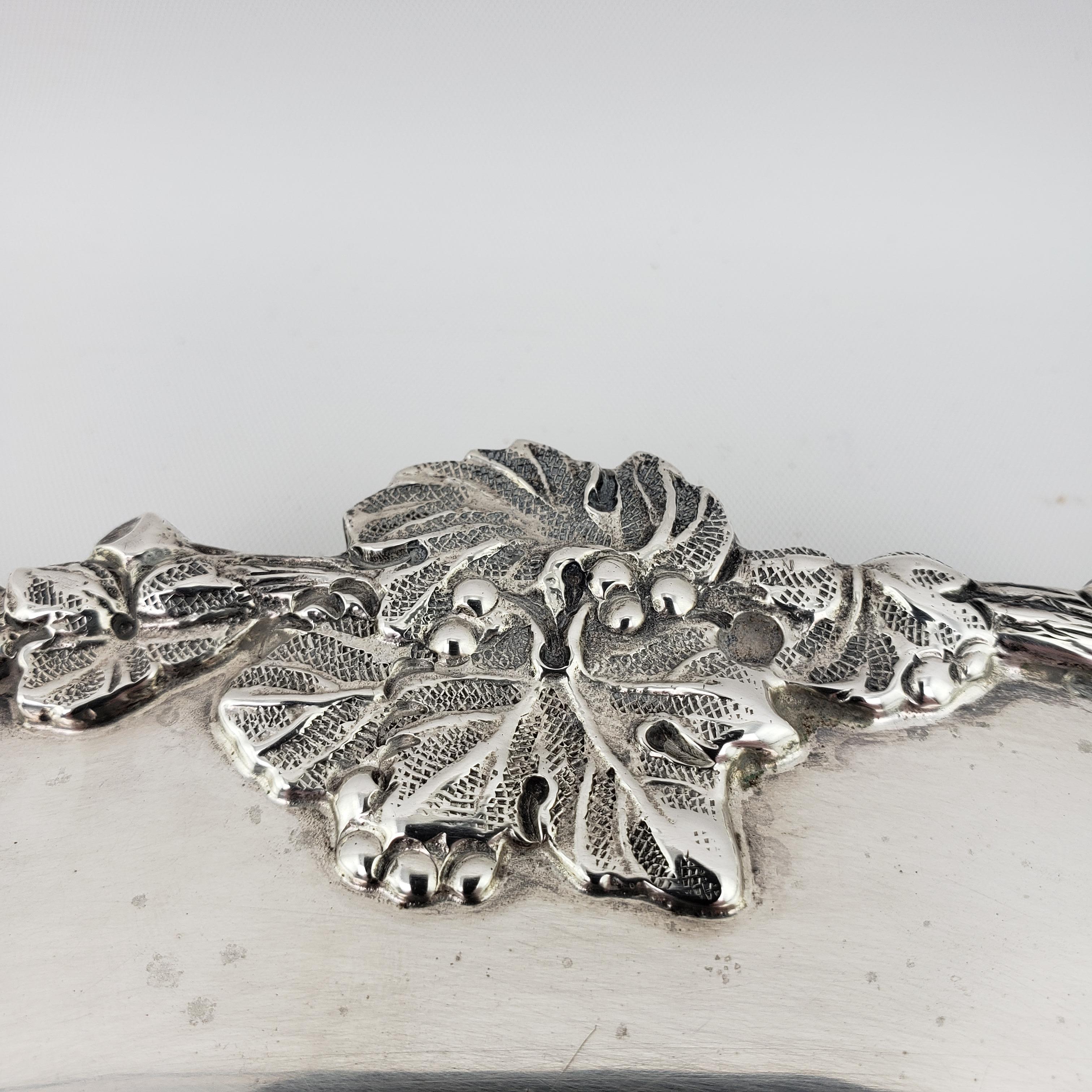 Round sterling silver serving tray featuring a raised border with a decorative grapevine motif. Weight: 1382 grams.