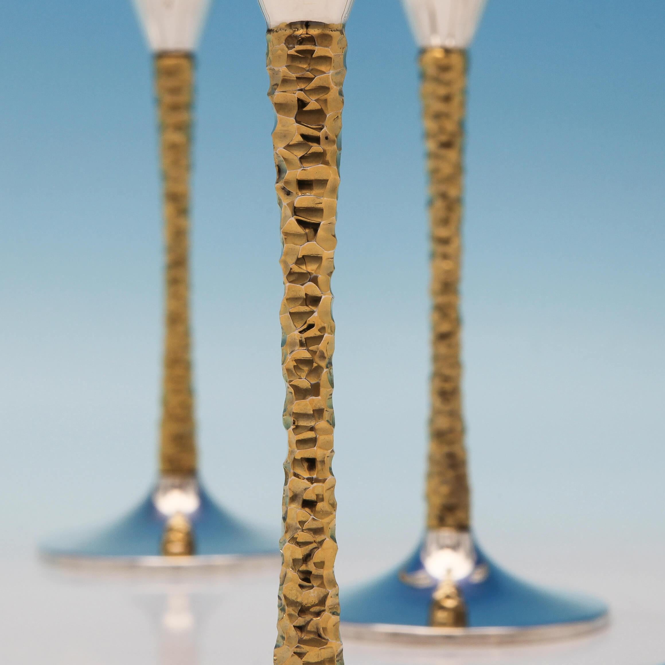 Hallmarked in London in 1977-1980 by Stuart Devlin, this extraordinary set of 12, Elizabeth II, parcel gilt sterling silver Champagne flutes are elegant in design, with gilt bark effect stems in the typical Devlin style. Each Champagne flute
