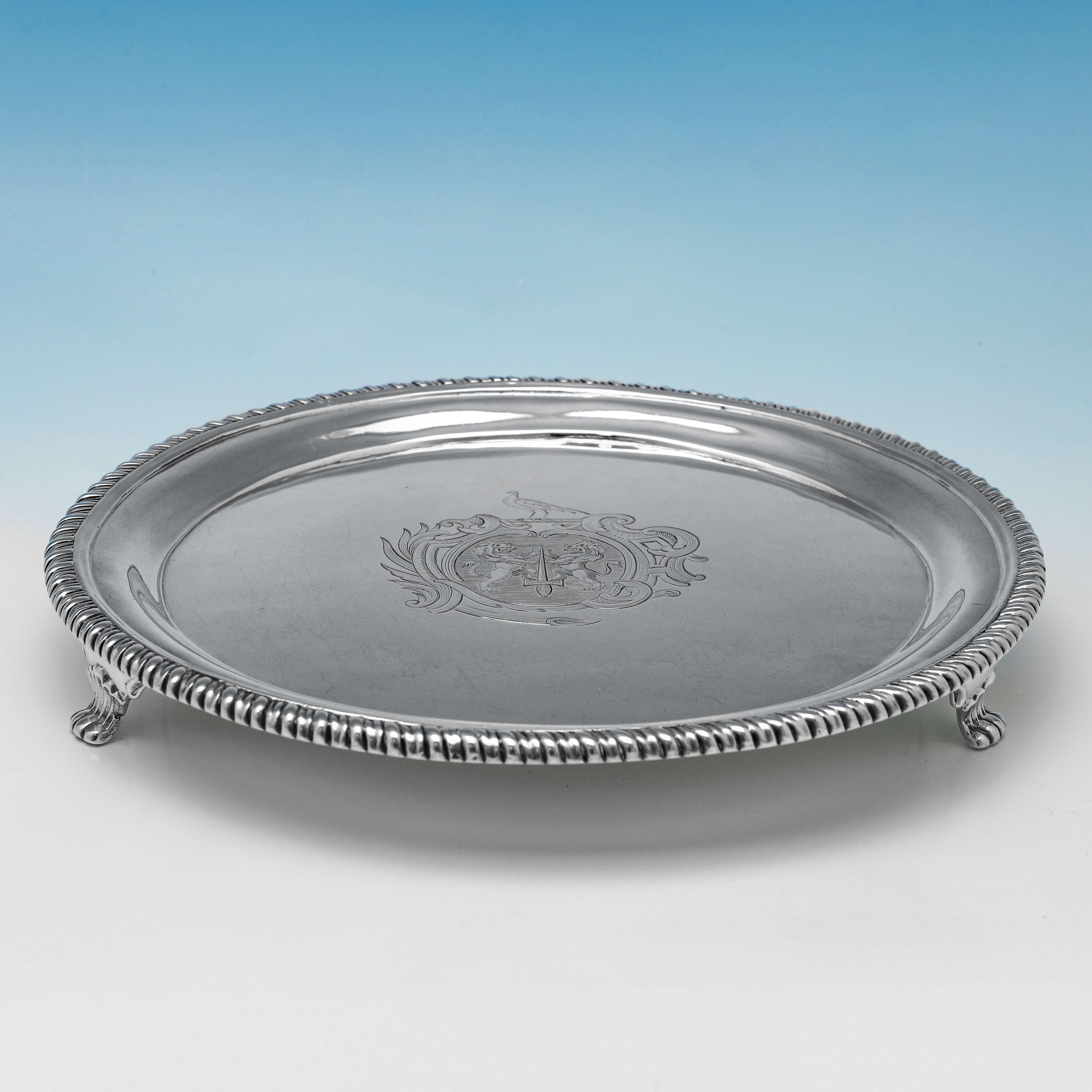 Hallmarked in London in 1759 by John Cafe, this George II, Antique Sterling Silver Salver, features a gadroon border and lion paw feet. The salver measures 1