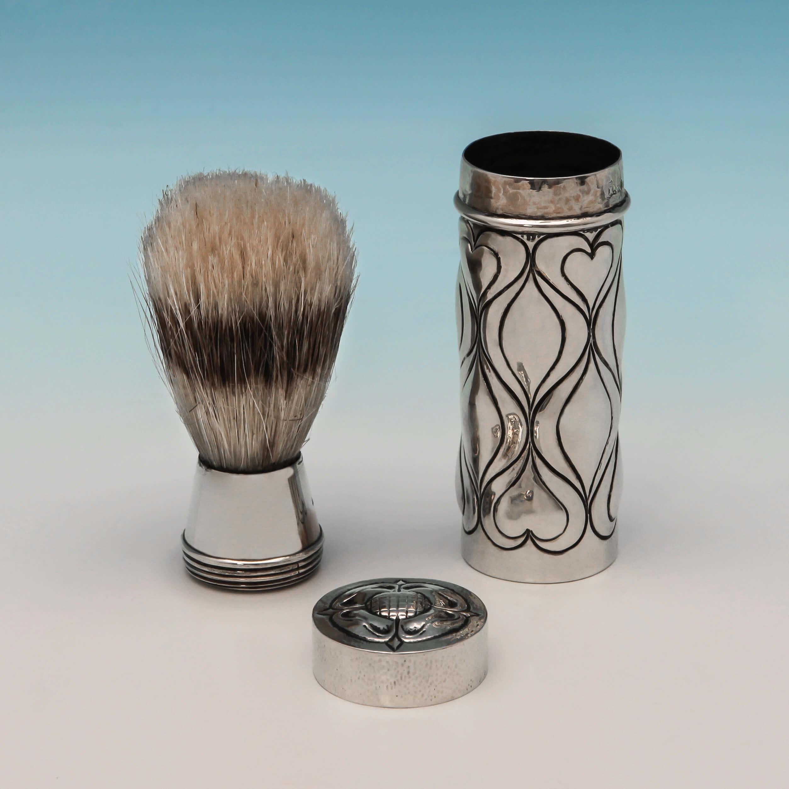 Hallmarked in London in 1900 by Ramsden & Carr, this stylish and rare, sterling silver shaving brush, is in the Arts & Crafts style, with chased decoration to the body, a hand hammered finish, and a badger hair brush. This shaving brush measures