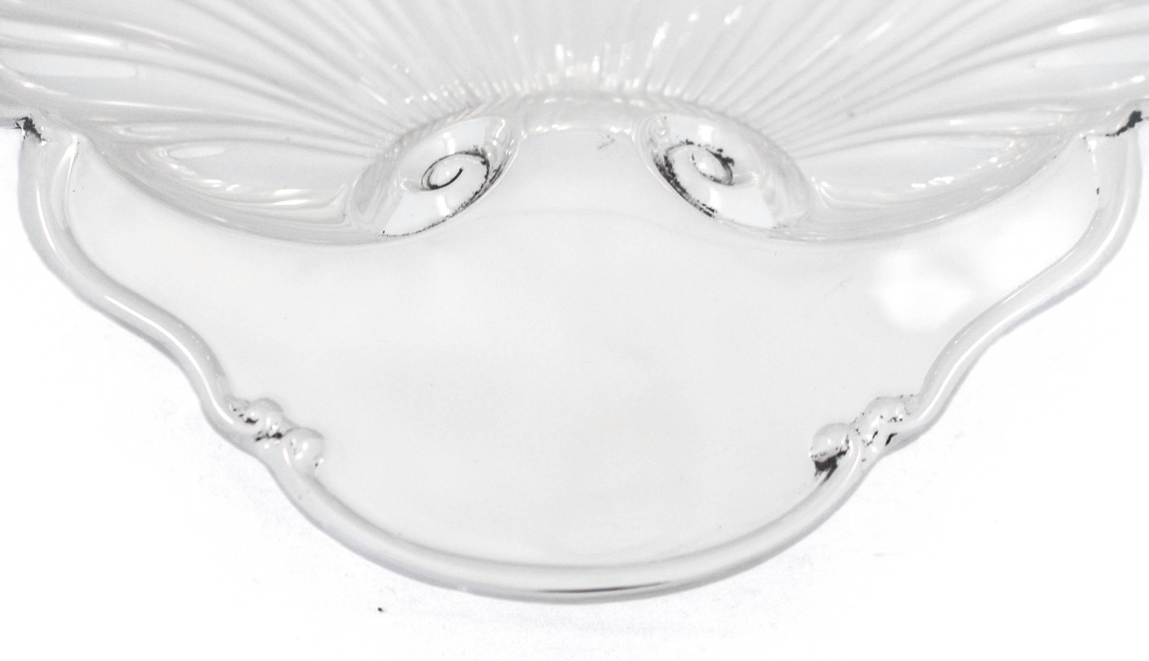 Being offered is a large sterling silver dish by Mueck-Cary Silver.  It stands on three feet; one in the front center and the other two in the back on either side.  The rim is scalloped and at the top there’s a flat surface for a monogram or