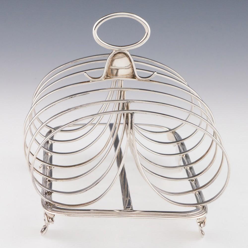 Heading : Sterling silver six division toast rack.
Date : Hallmarked in London 1833 For Thomas Johnson.
Period : William IV
Origin : London England
Decoration : Three spar with double loop divisions. Omega handle and cast feet
Size : Height