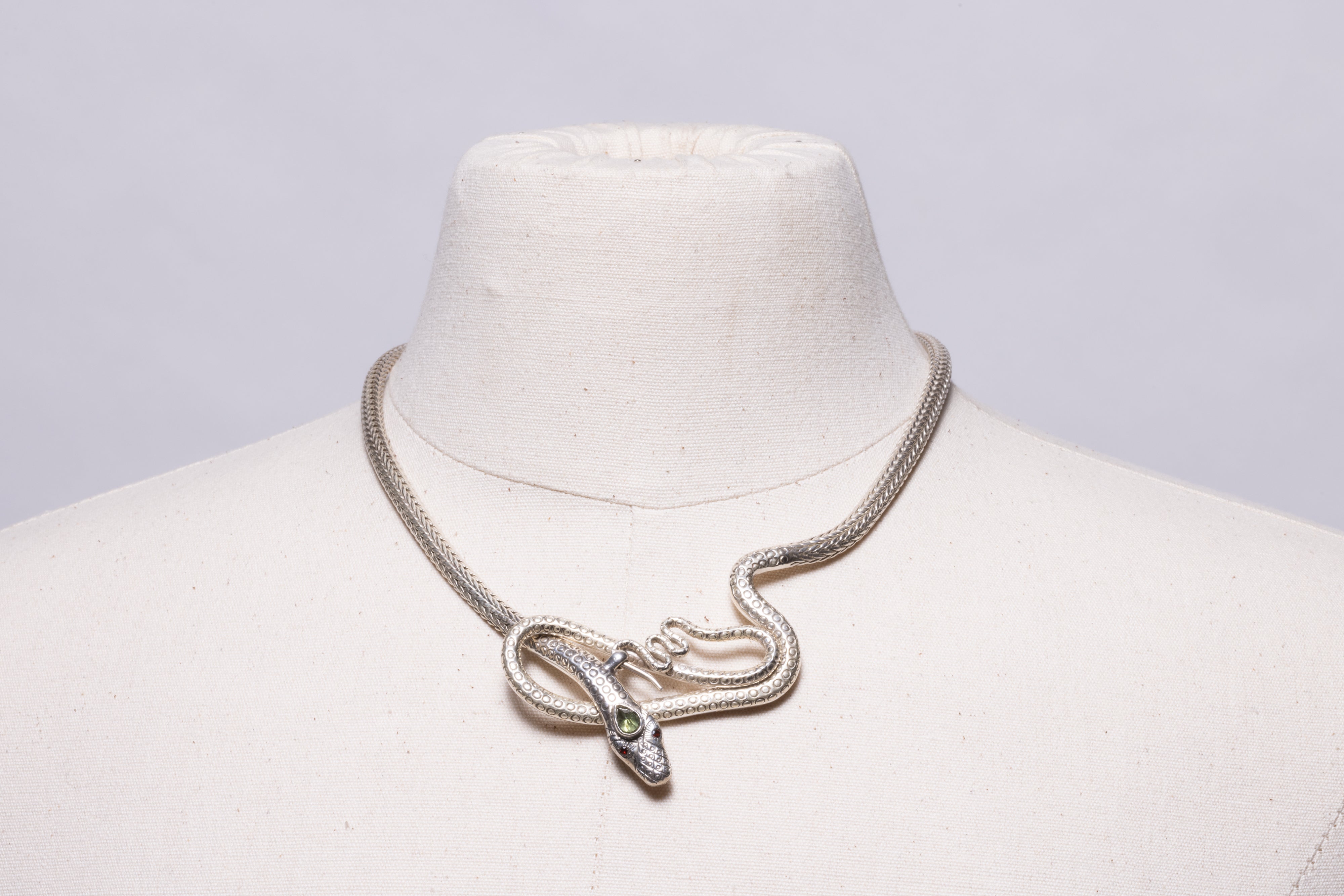 Una collana con catena a serpente con motivo a spina di pesce condensato, con un serpente ad anello nella parte anteriore con occhi sfaccettati in granato e un terzo occhio sfaccettato a forma di pera in peridoto.  La chiusura è sul davanti.

La