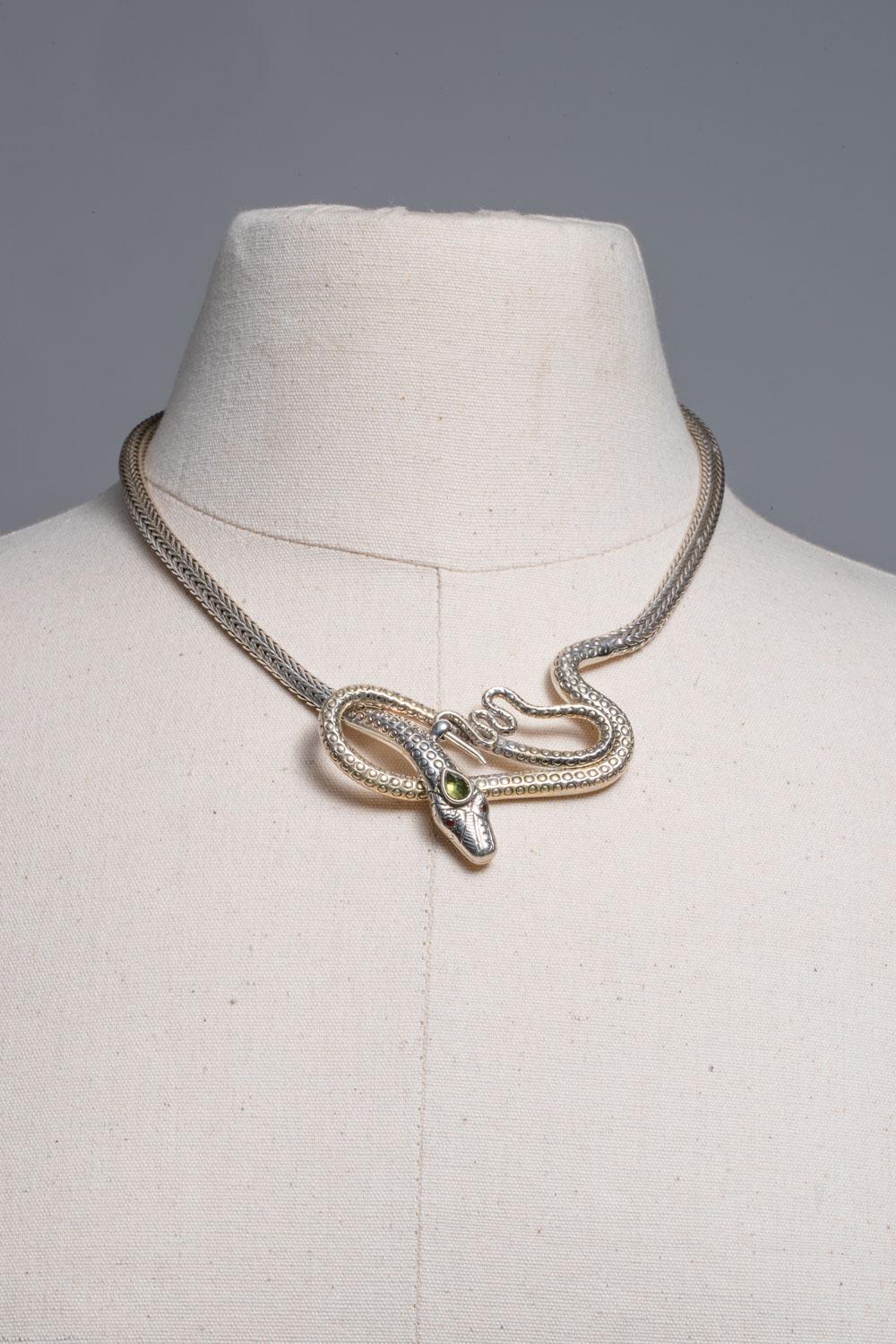 An exceptional hand-tooled and woven sterling silver coiled snake necklace with a faceted pear-shaped peridot third eye and faceted garnet eyes.  The clasp is in front and just below the head it hooks onto the tail.  Inside circumference is 16