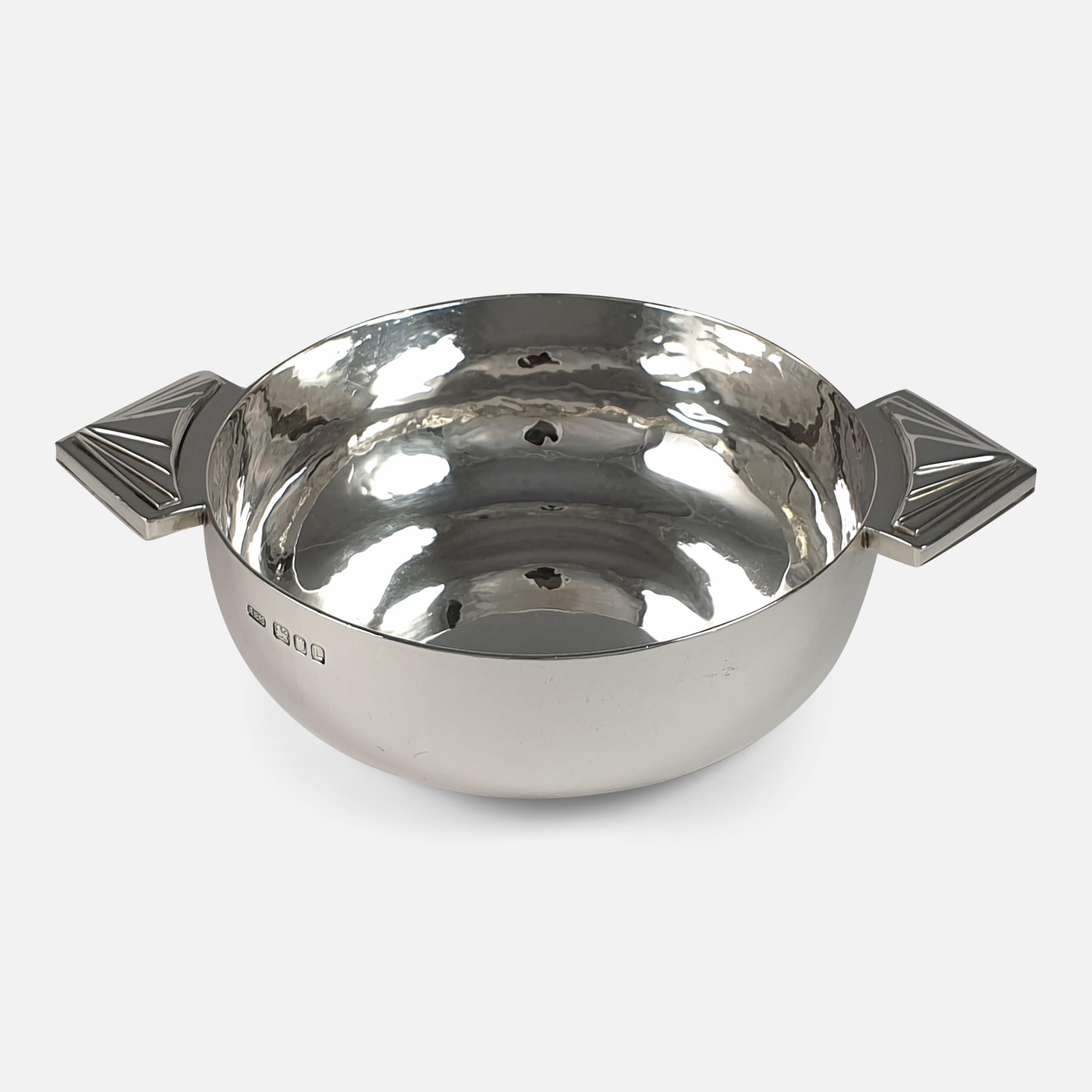 A George VI sterling silver Quaich in the Art Deco style; hallmarked London, 1946, and made by highly collectable silversmith R.E. Stone. The Quaich is of circular spot-hammered form, with triangular geometric design applied to the