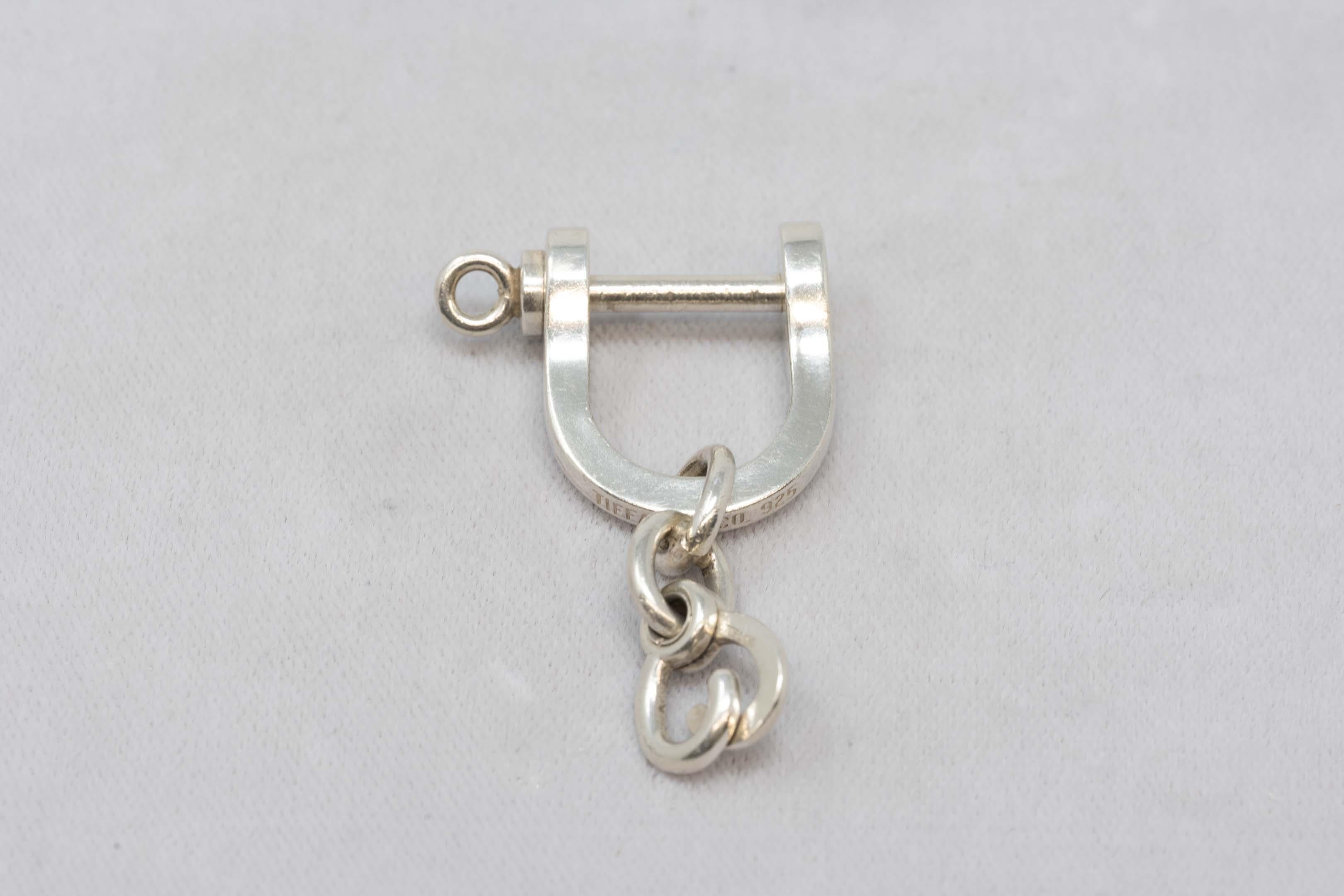 Tiffany & Co sterling silver stirrup keychain preowned, some scratches. Signed Tiffany & Co. 925. Measures 2 inches long x 1 1/4 inches wide. Made in the USA, late 20th century.