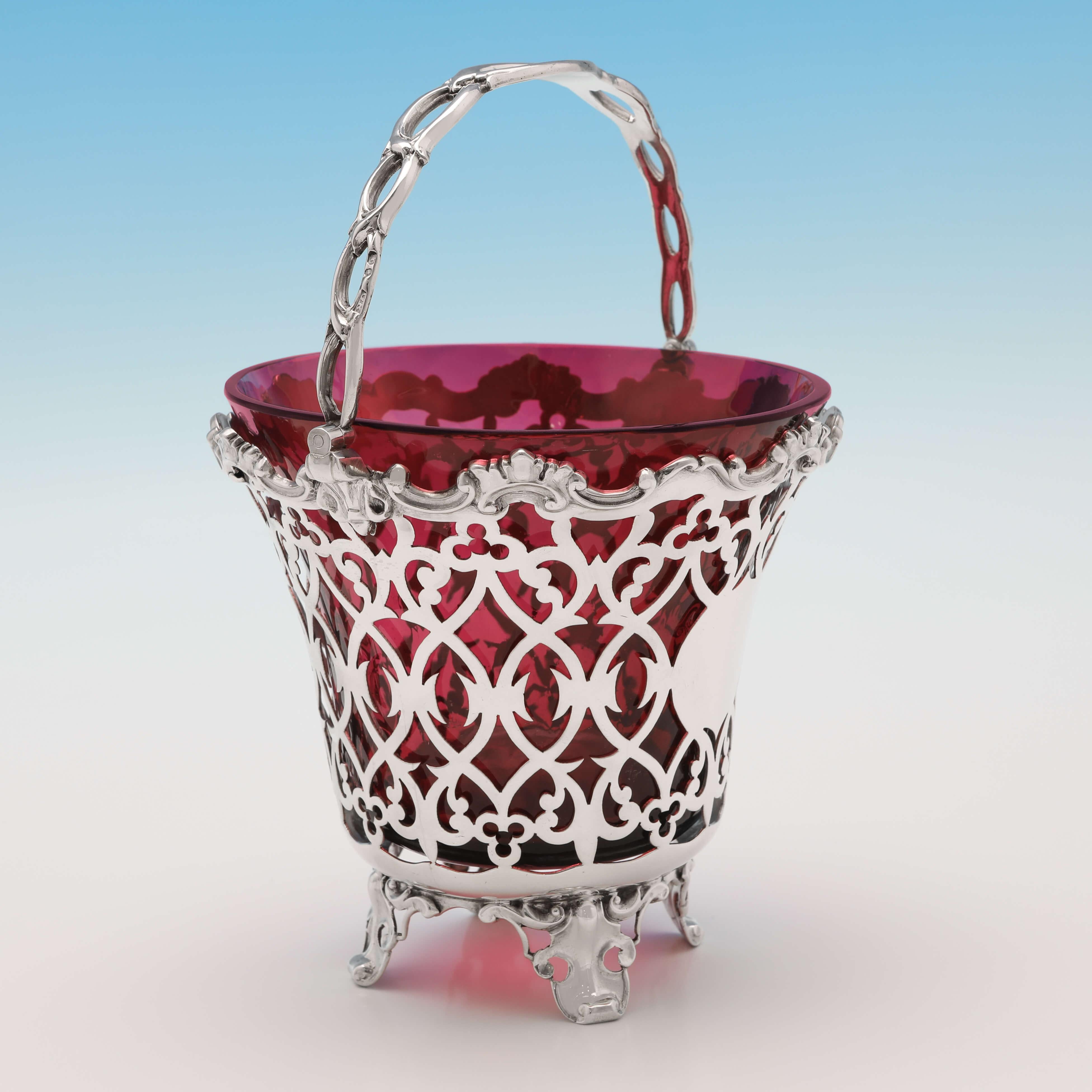 Hallmarked in London in 1856 by George Richards, this attractive, Victorian, Antique Sterling Silver Sugar Basket, features a ruby glass liner, and ornate pierced decoration to the body. The sugar basket measures 7