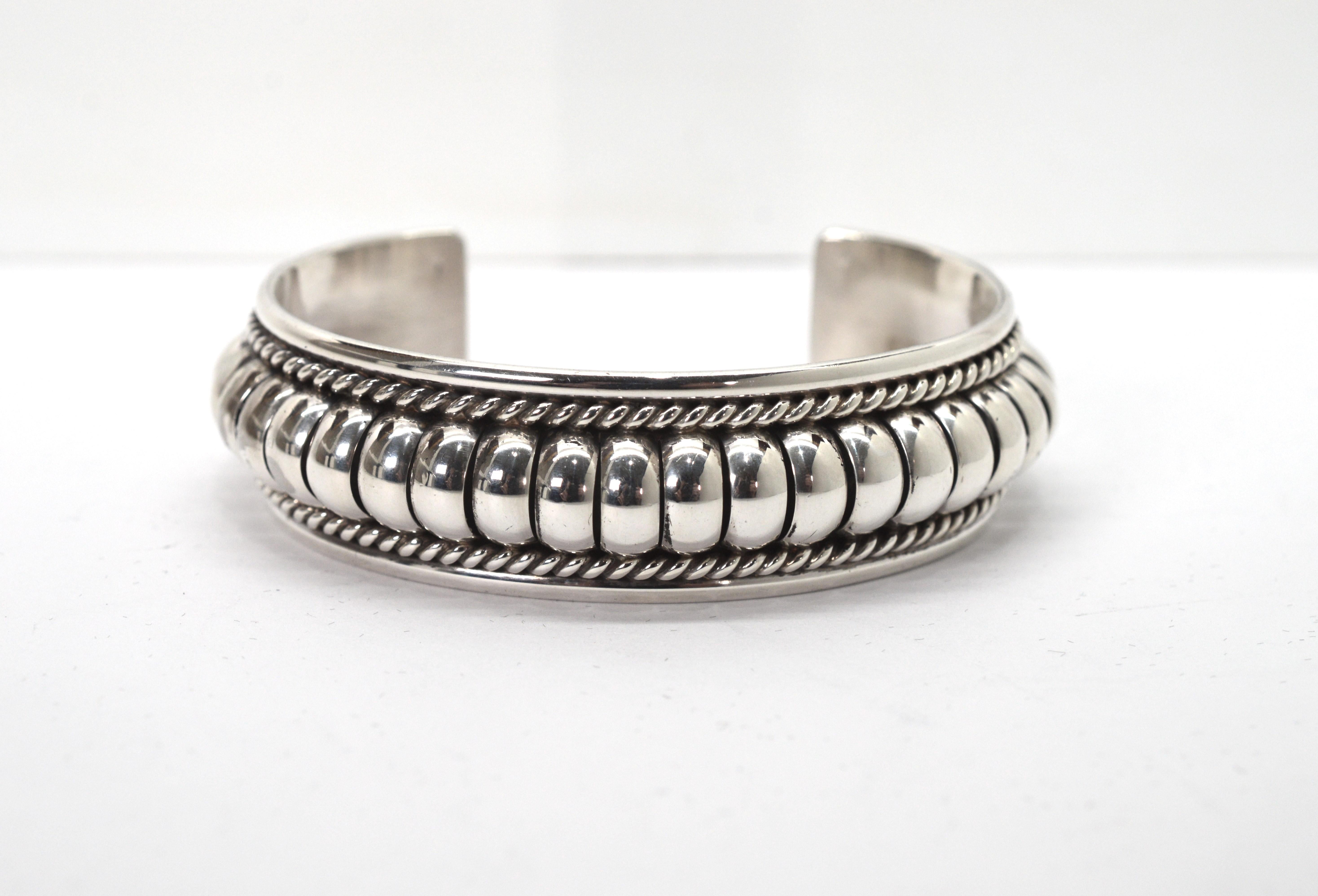 This beautifully crafted sterling silver cuff by Navajo artist, Thomas Charley,  features his signature style of dimensional design with domed silver bars framed with borders of twisted sterling ropes. This unique signature TC 