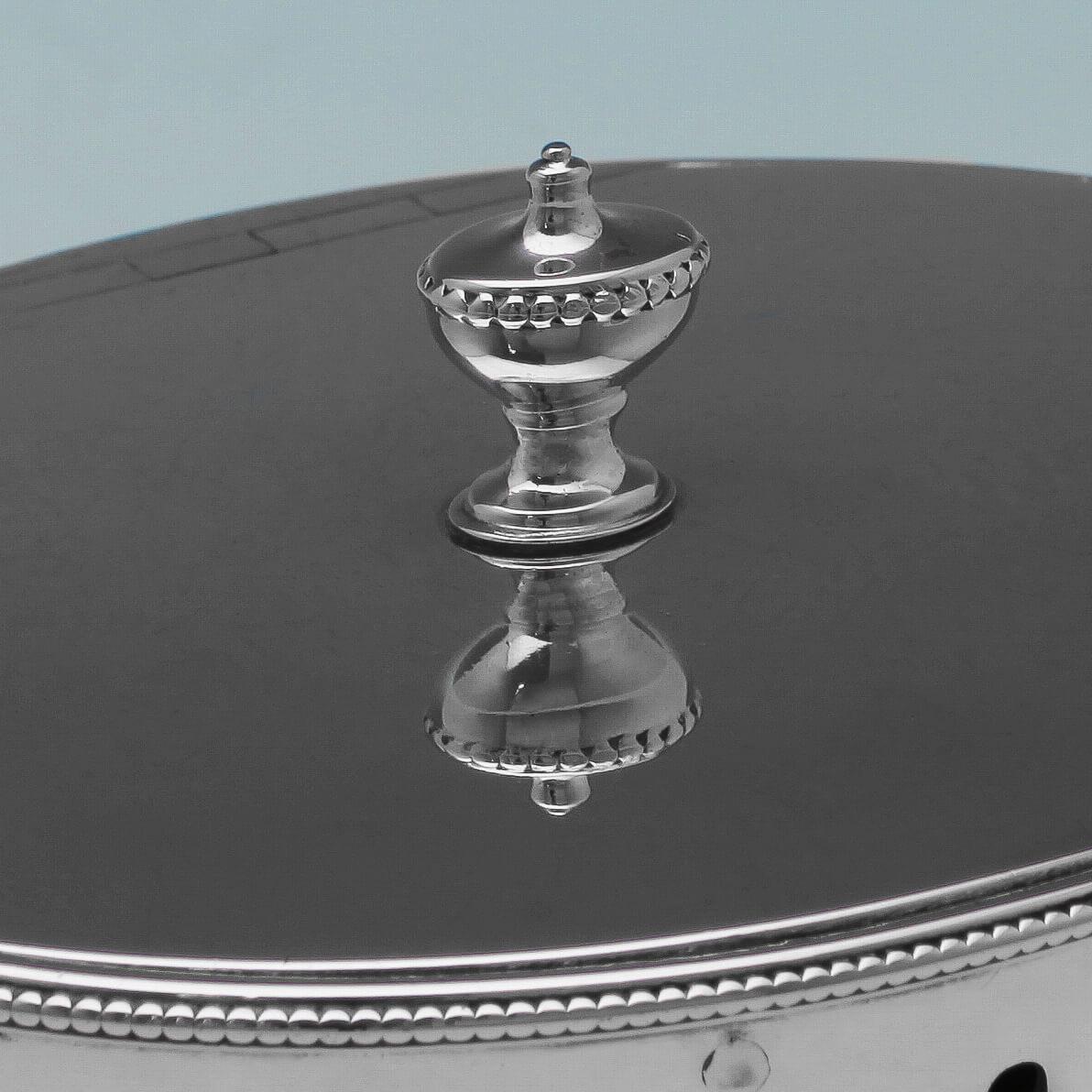 Hallmarked in London in 1780 by Hester Bateman, this elegant, George III, antique, sterling silver tea caddy is pleasingly simple, with a plain oval body decorated top and bottom with a thin band of beading and featuring an original crest. The tea