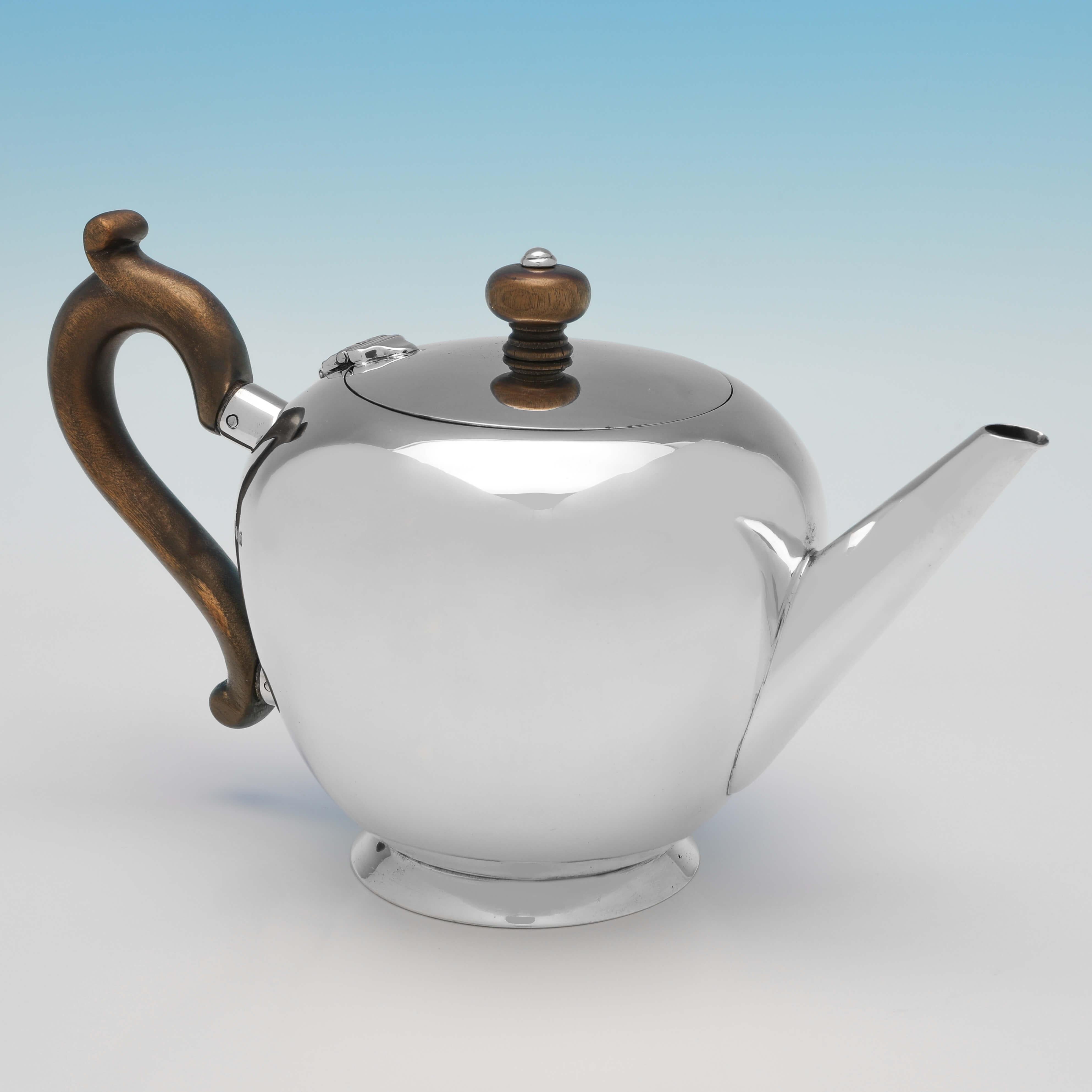 Hallmarked in London in 1931, this handsome, sterling silver teapot, is in the 'Bullet' shape, plain in style, and with a wooden handle and finial. The teapot measures 5.25
