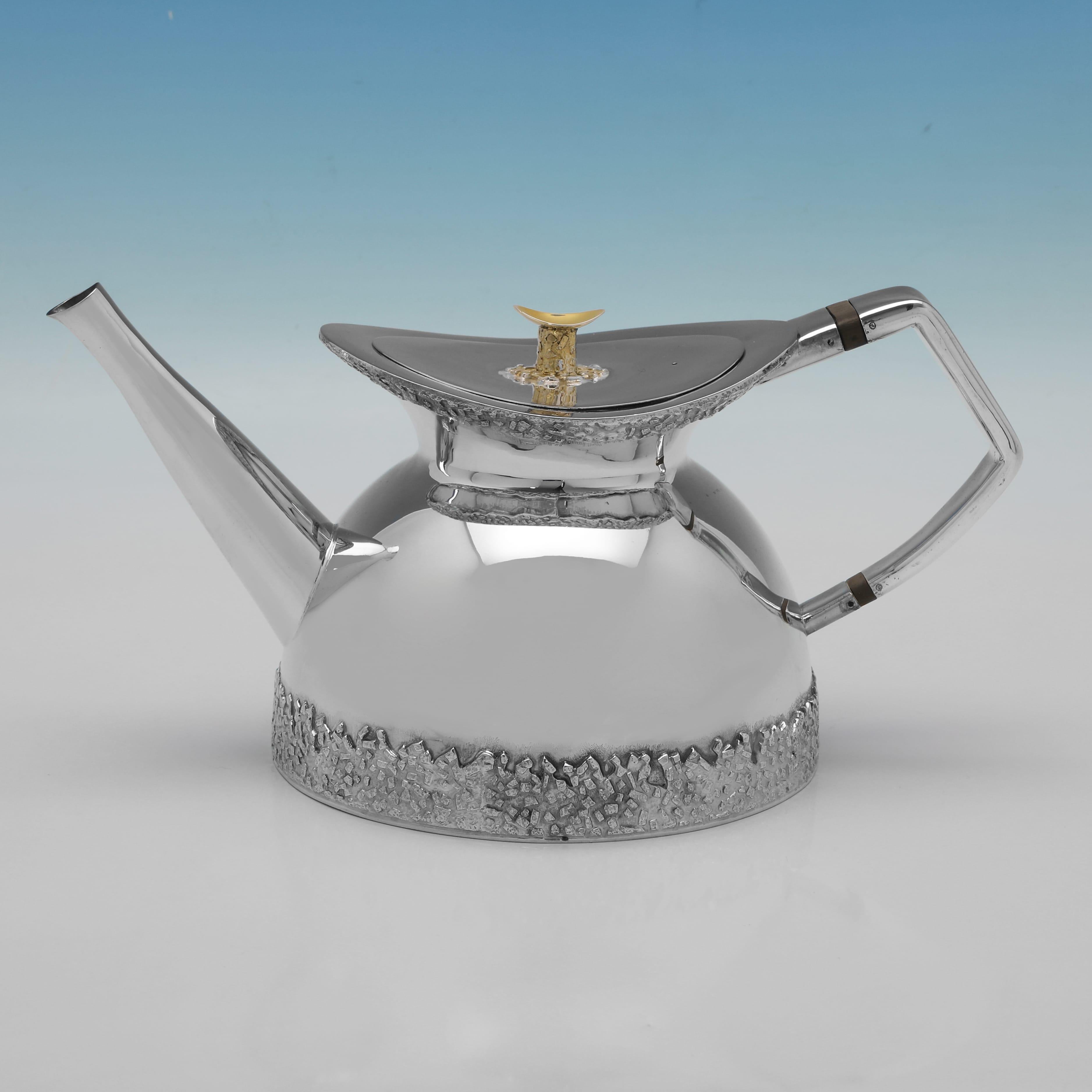 Poinçonné à Londres en 1975 par Michael Benstead, ce remarquable service à thé trois pièces en argent sterling Elizabeth II est un excellent exemple du design moderne du milieu du siècle dernier. L'ensemble présente une bordure inférieure texturée