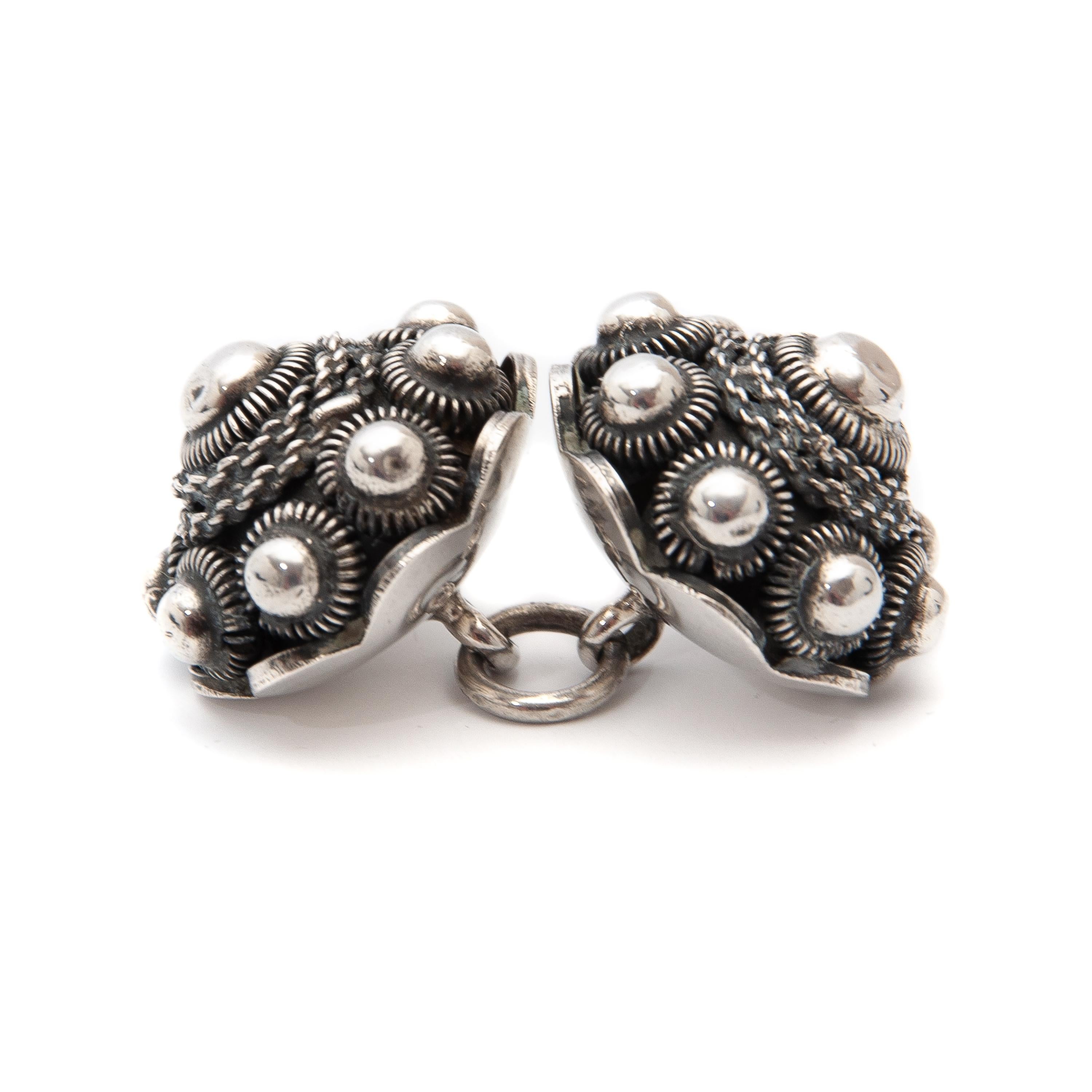 This pair of antique sterling silver Zeeland throat knots are set with an intermediate ring. The knots or buttons were worn by Dutch Zeeland men and are part of the Walcher traditional regional costume in the Netherlands around 1900. They were worn