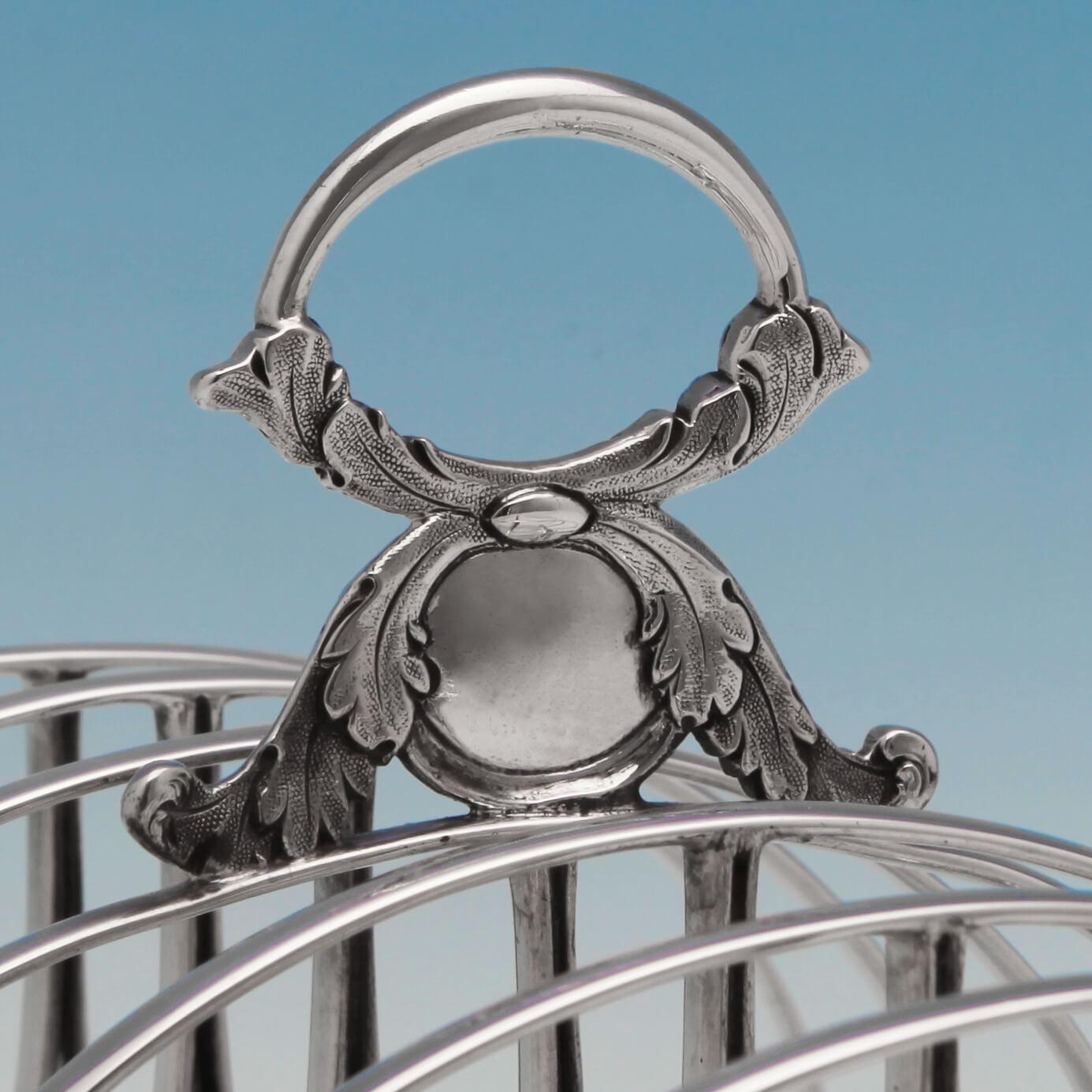 Hallmarked in Edinburgh in 1827 by Alexander Edmonstoun III, this antique, George IV sterling silver toast rack, has generously spaced, looped dividers and stands on a rectangular gadroon bordered base with acanthus and claw feet and an acanthus