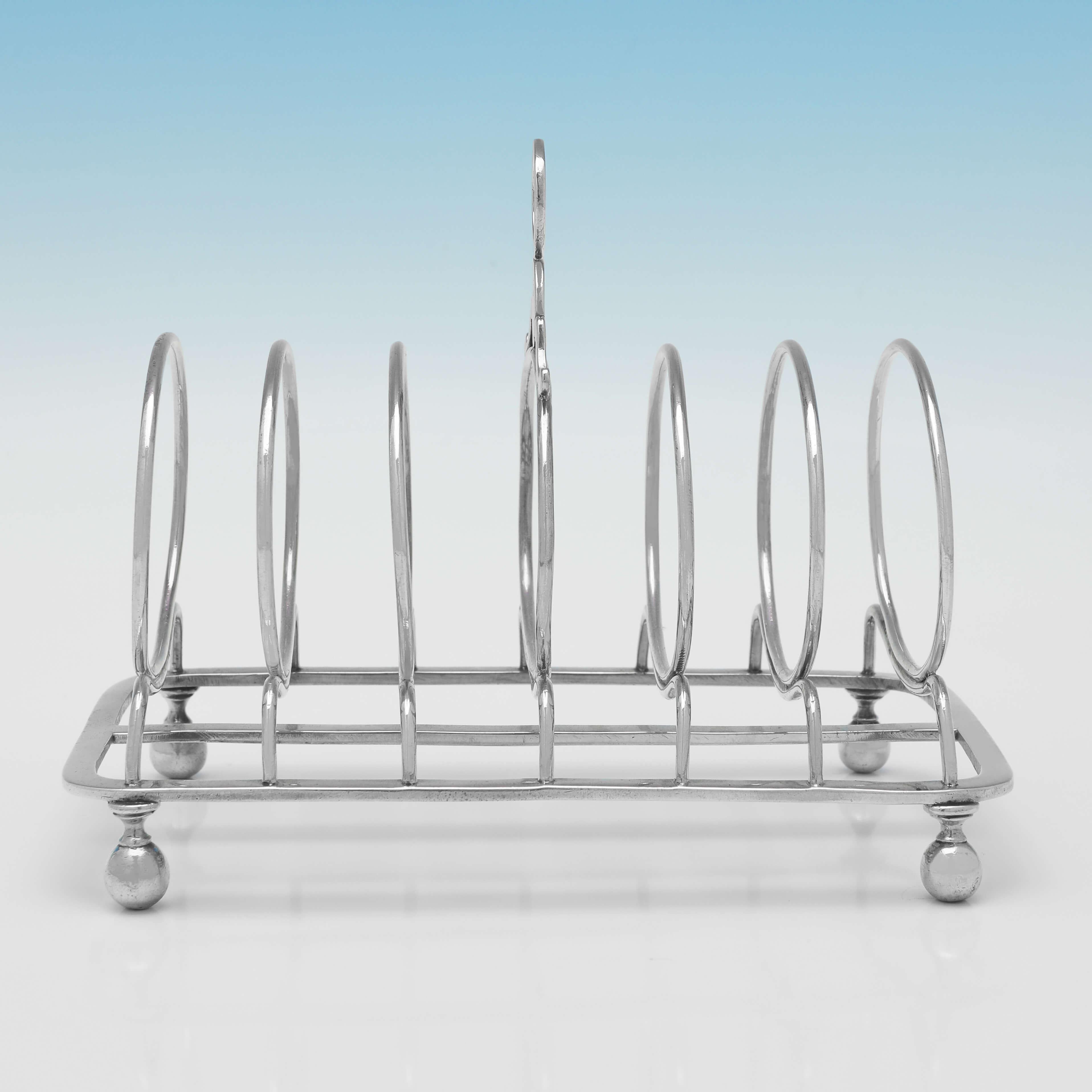 Hallmarked in London in 1805 by John Emes, this very handsome, George III, Antique Sterling Silver Toast Rack, is plain in style, standing on 4 ball feet, and holding 6 slices of toast. The toast rack measures 4.75