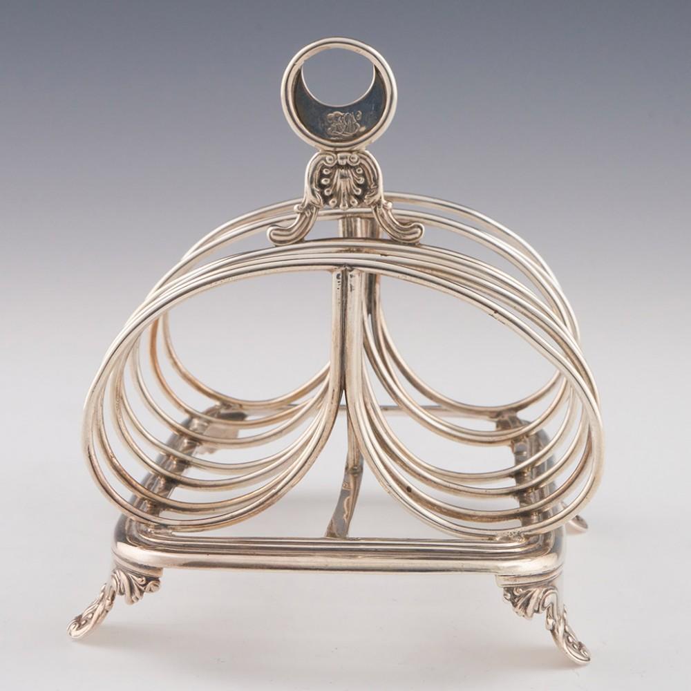 Heading : Sterling silver toast rack
Date : Hallmarked in London in 1833 for Charles Fox II
Period : William IV
Origin : London, England
Decoration : Six divisions with double loop dividers. Ring 'omega' handle with scrolled acanthus leaf and