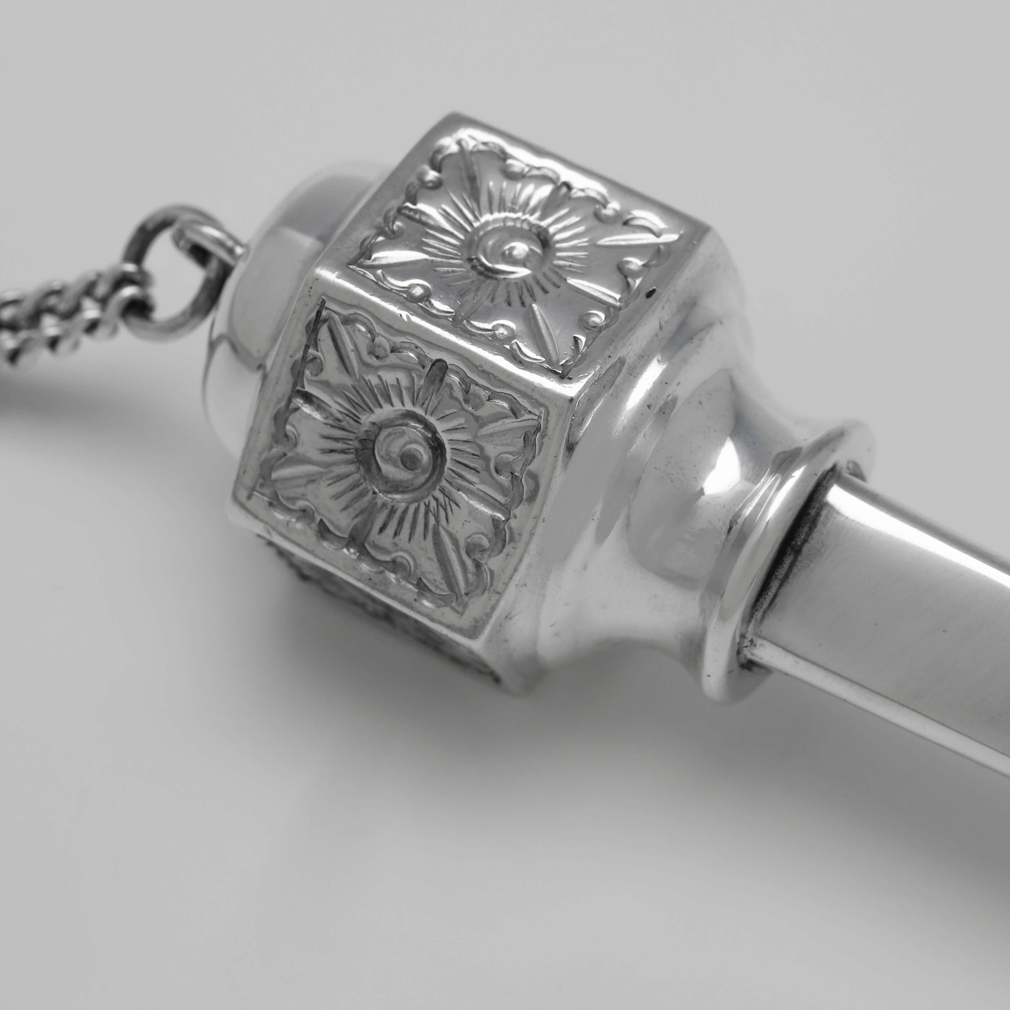 Poinçonné à Londres en 1929, ce charmant Yad, ou pointeur de Torah, en argent sterling, est de forme traditionnelle. 

Le yad mesure 29 cm de long, 4 cm de diamètre et pèse 5 onces troy. La chaîne mesure 36 cm de long.