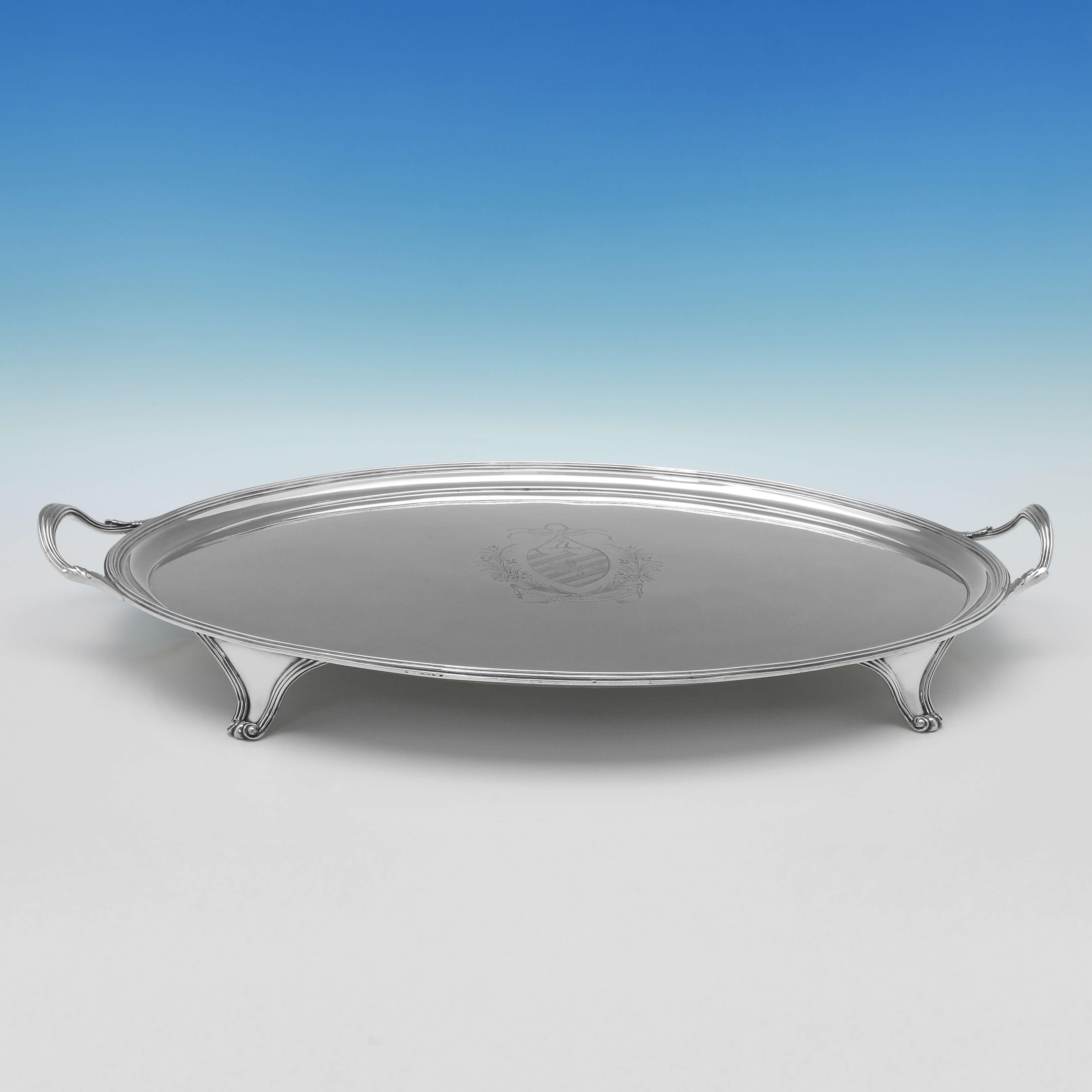 Hallmarked in London in 1794 by George Smith II & Thomas Hayter, this very handsome, George III, antique Sterling Silver tray, stands on four scroll feet, and features reed borders and an engraved coat of arms and motto to the centre. The tray