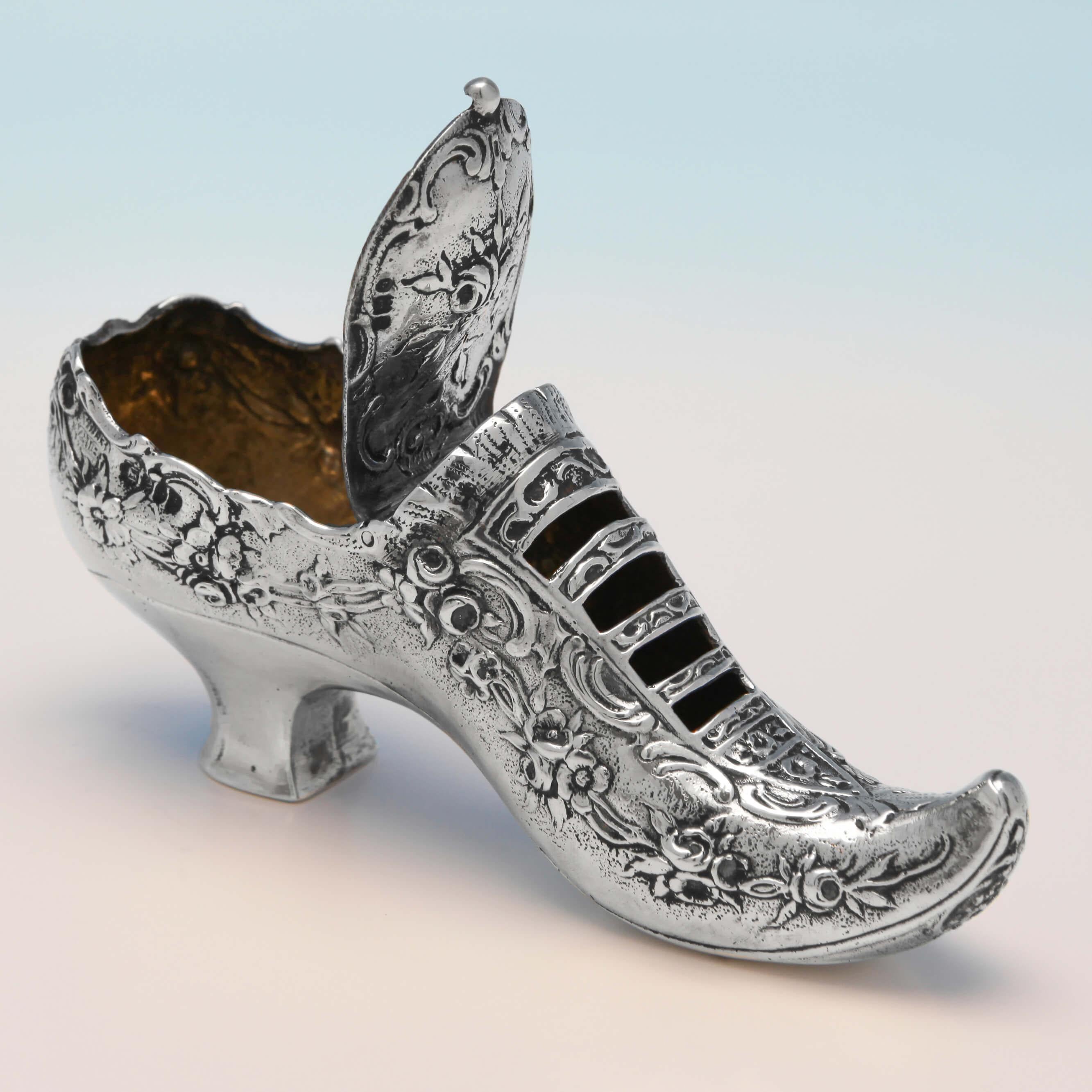 Carrying import marks for London in 1900, this novelty, Victorian, antique sterling silver trinket box, is in the form of a shoe, with a gilt interior, a hinged lid, and chased decoration throughout. The box measures: 2