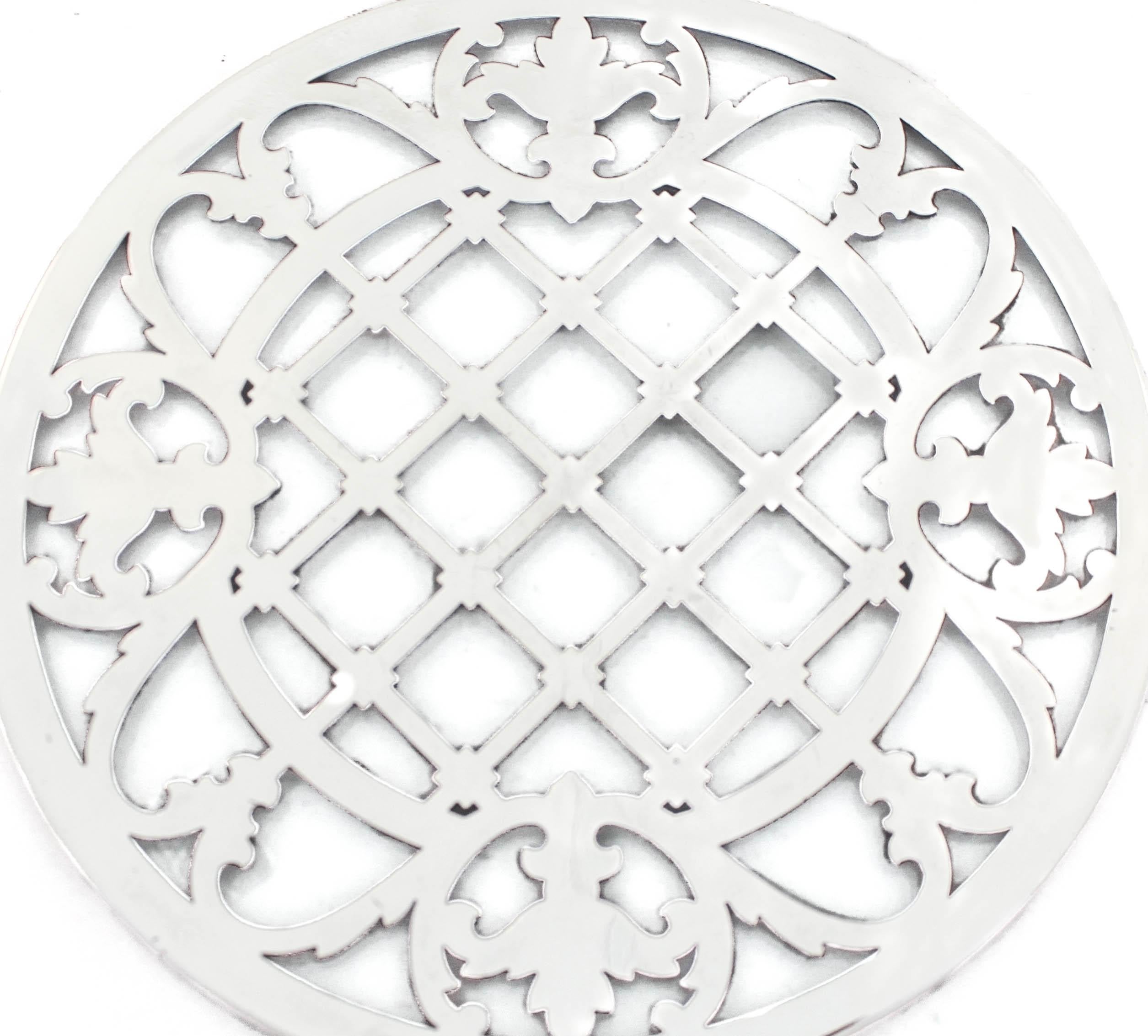 Being offered is a sterling silver trivet (with glass underneath) made by the Webster Silver Company.  It has a beautiful cutout pattern in the center of squares and around the edge a floral design. 
Sterling silver trivets are so much nicer on your
