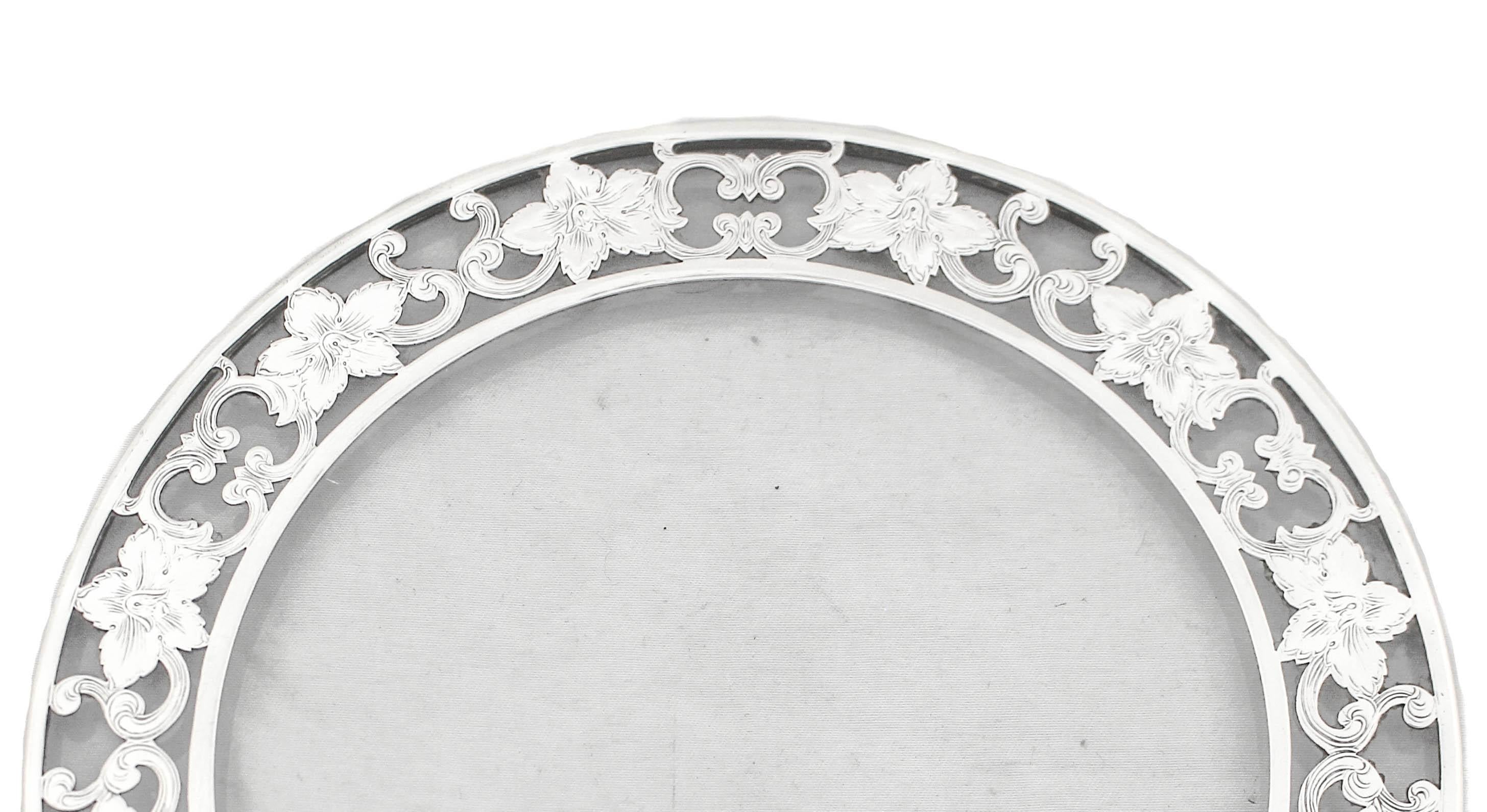 Being offered is a sterling silver trivet with overlay glass. A lovely floral motif decorated the edge and folds over the rim.  A great piece to put under a vase or perfume bottles on …of course, to use as a trivet when serving food.