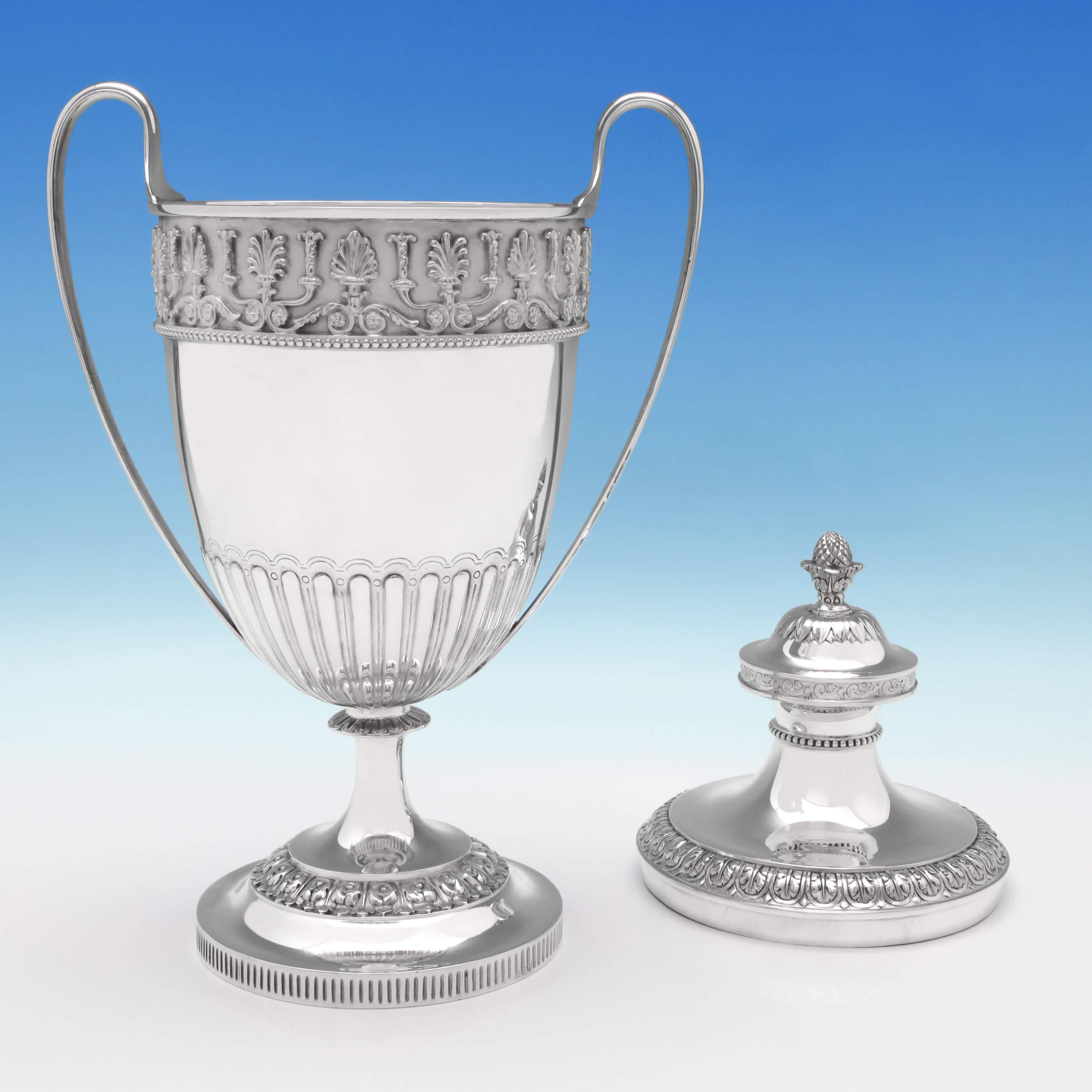 Hallmarked in London in 1872 by C. F. Hancock & Co., this exceptional, Victorian, antique, sterling silver trophy, features fluted decoration, loop handles, a cast and applied frieze, and a pineapple finial. The trophy measures 15