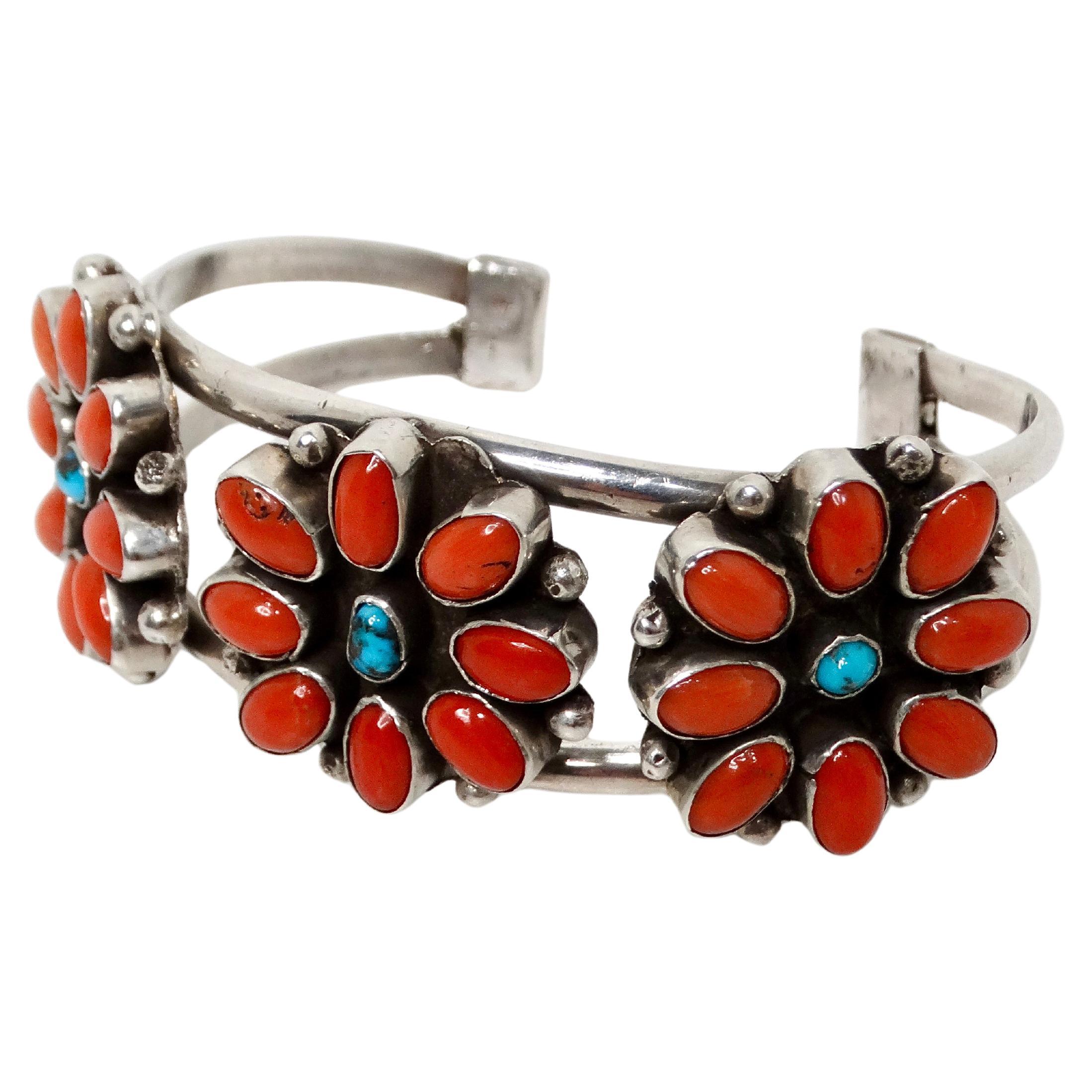 Ce bracelet manchette en argent sterling, orné de fleurs de turquoise et de corail, datant des années 1970, est un magnifique exemple de l'art de la joaillerie ancienne. Son design audacieux présente un travail complexe en argent sterling avec des