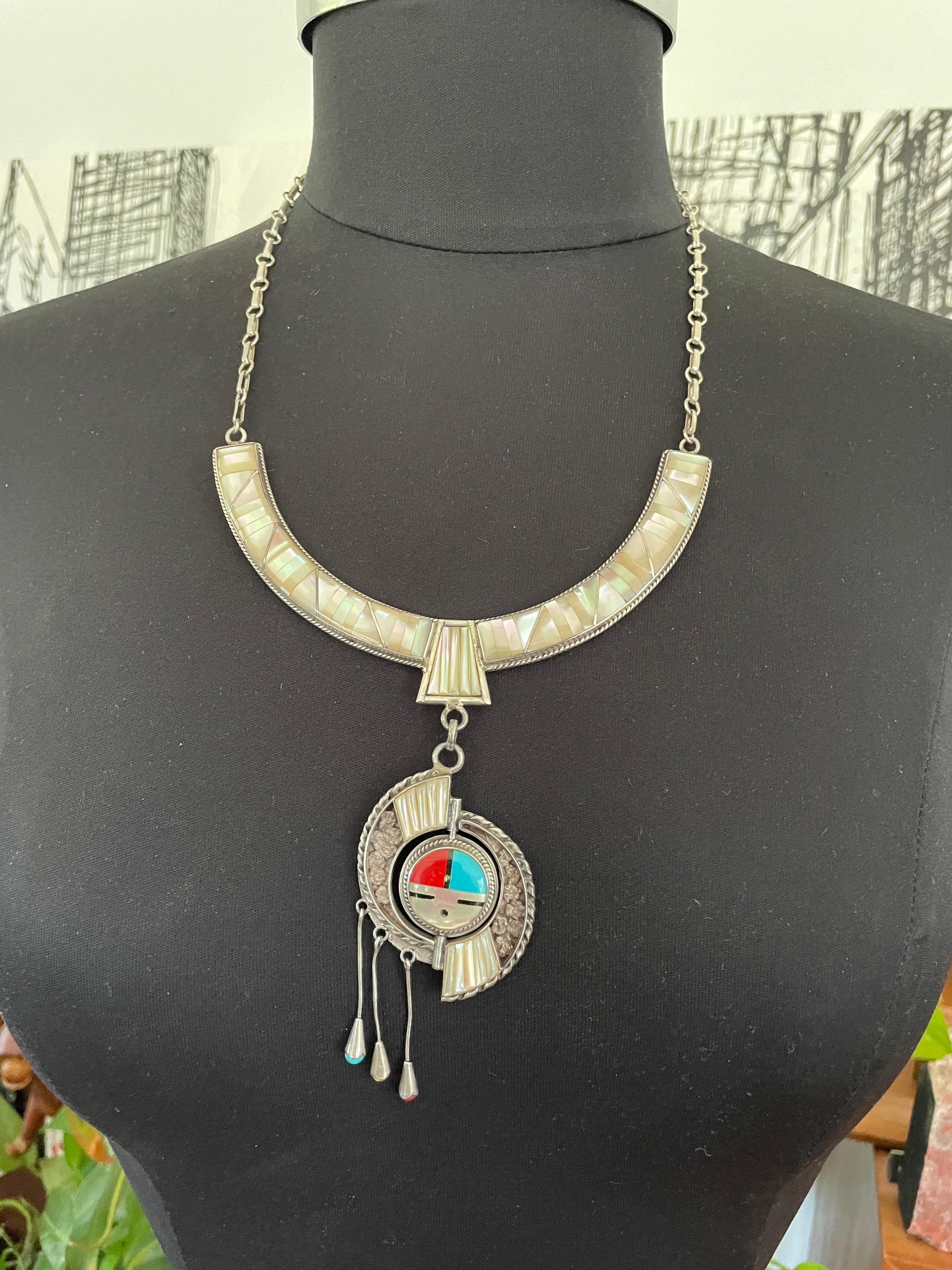 Splendida collana con volto solare, corallo, turchese e madreperla incastonati in argento sterling. 3 pendenti con pietre incastonate. La misura è di 26 in totale. L'ogiva misura 3 pollici, il collare è largo 0,50 pollici. Si tratta di un'enorme