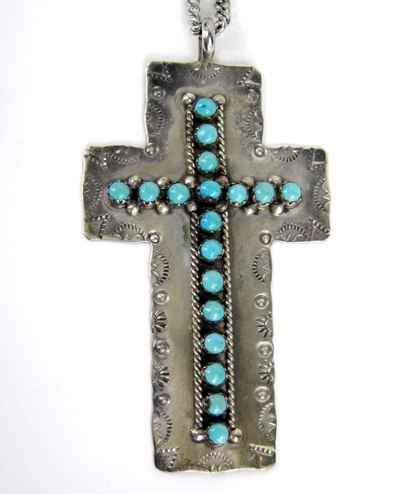 Wonderful Zuni Sterling Silver Cross with 18 turquoise cabochons set in serrated bezels. Traditional stamping around the edges of the sterling silver cross measuring 2 7/8” tall by 1 1/2” wide with a 1/8 in bail opening. Sterling silver chain