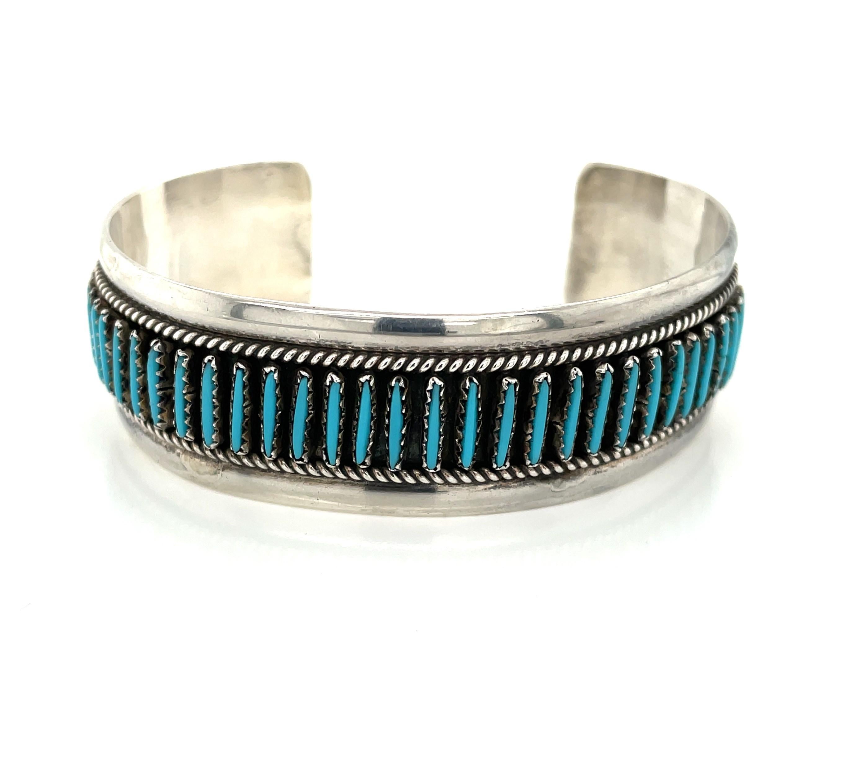 Turquoise needlepoint accents highlighted by a twisted silver rope detailing decorate the front placket of this sterling silver South West style cuff bracelet. Of a medium 3/4 inch width, this piece is a great casual accessory on it's own or as a