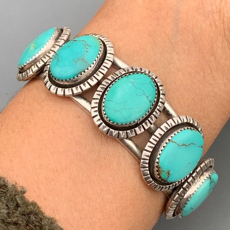 A stunning vintage Navajo cuff bracelet, handcrafted in sterling silver and featuring five beautiful oval-shaped turquoise cabochons, likely from the renowned Royston mine. The stones display intricate natural matrix patterns, adding unique