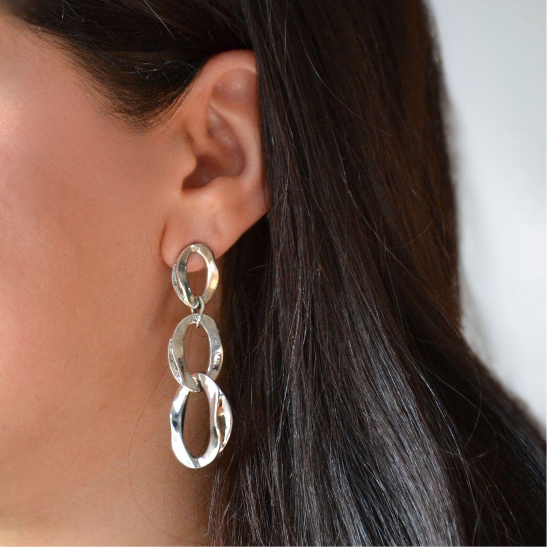 L'eleganza moderna incontra il movimento senza sforzo in questi orecchini a goccia a maglie aperte in argento sterling. Progettati con tre maglie ovali lucide, ciascuna caratterizzata da una leggera torsione per aggiungere dimensione, questi