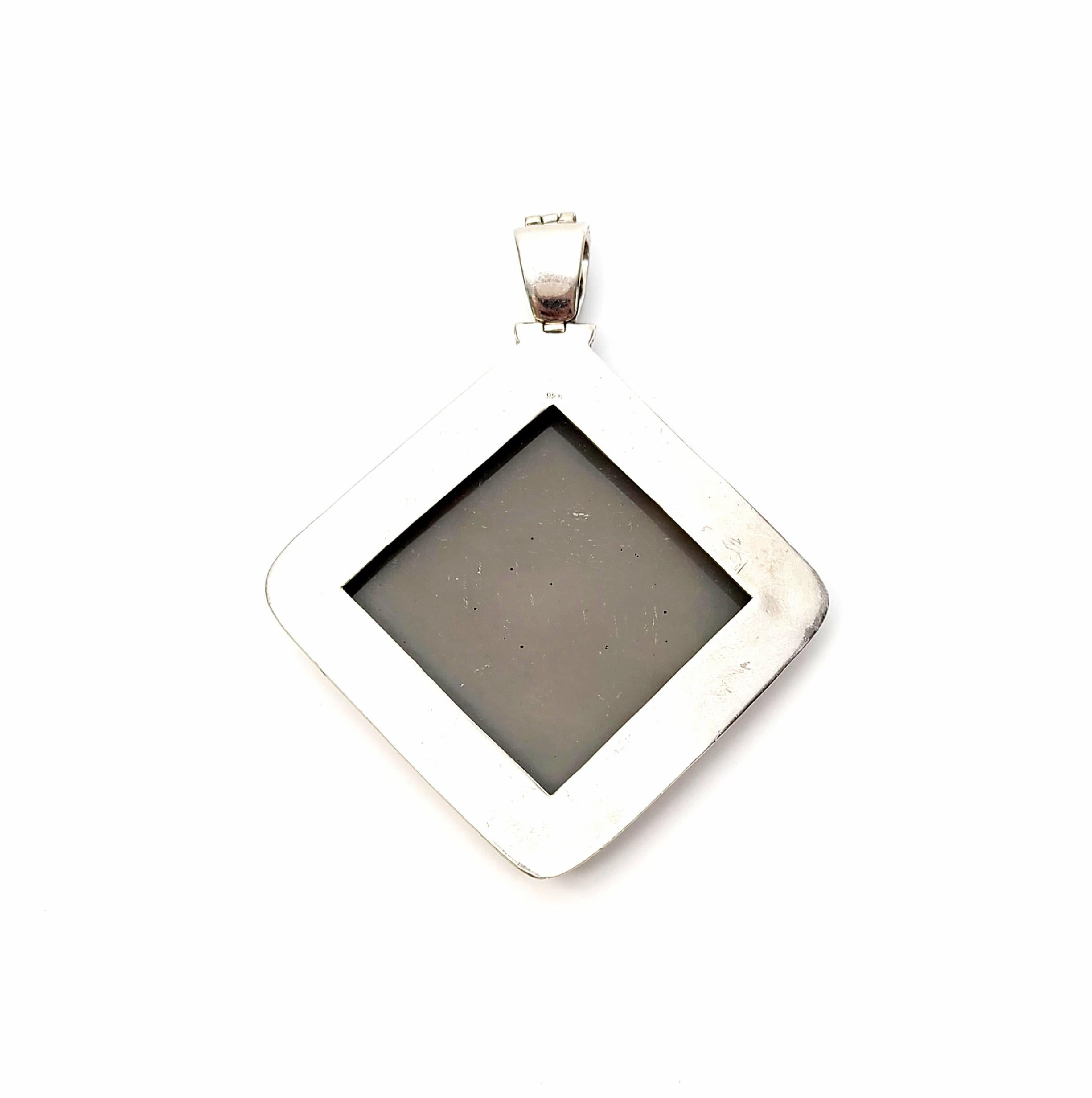 Large sterling silver pendant with copper, silk thread and rhinestone accents.

This unique and large handcrafted artisan piece features a large square sterling silver frame with copper accent edging surrounding a square with applied silk thread,