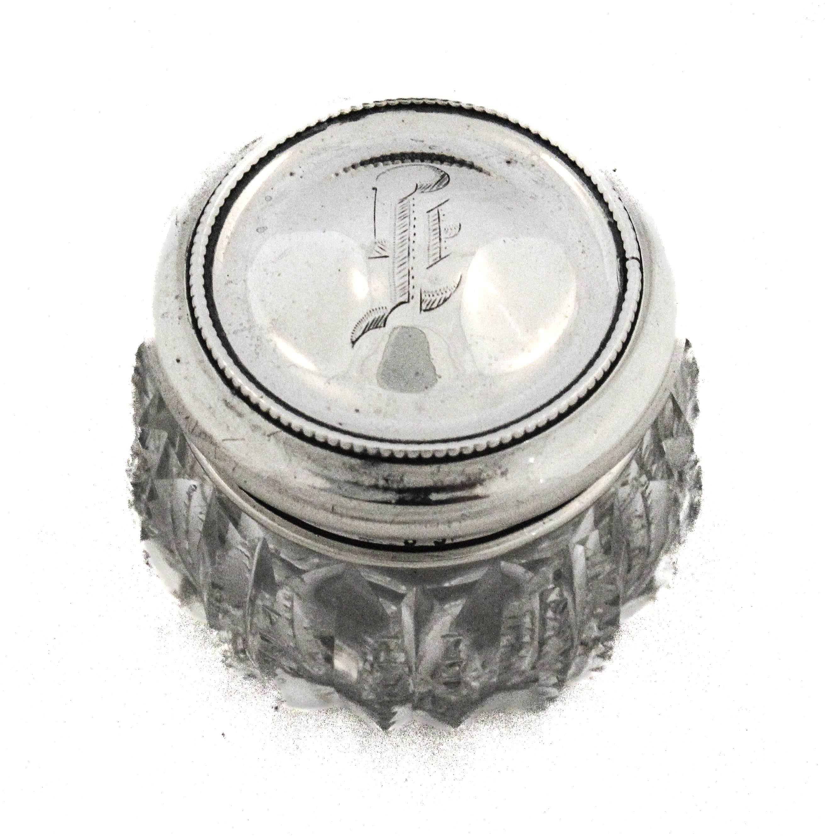 Questo affascinante vaso antico in cristallo tagliato con coperchio in argento sterling è stato prodotto da Wallace Silversmiths prima del 1900. Misurando 2 pollici di larghezza per 1,5 pollici di altezza, esemplifica la delicata abilità artigianale