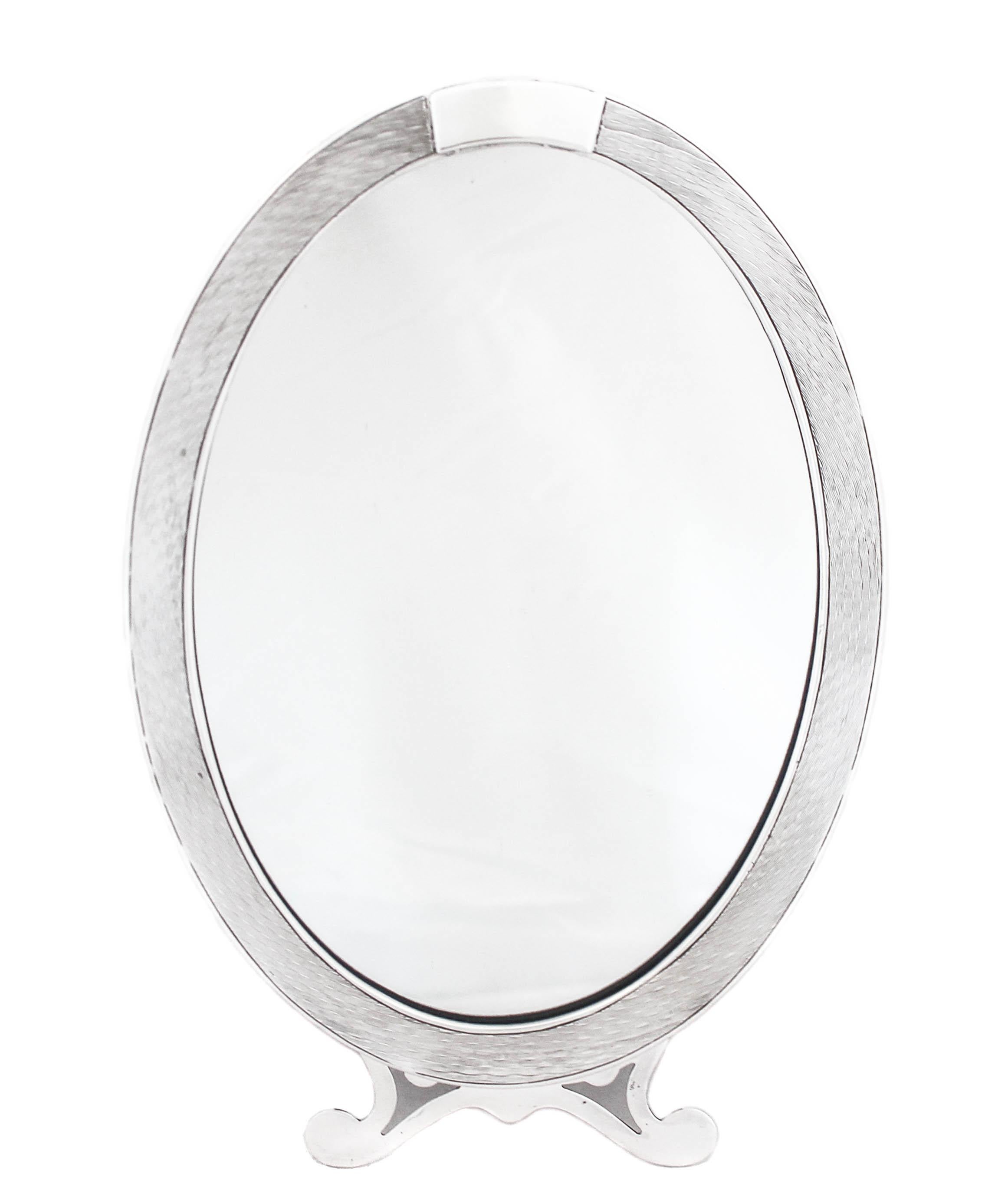 Being offered is a sterling silver vanity mirror from the early 20th century. Manufactured by the I. N. Deitsch silver company of New York. It has an engine-turned design on both sides with a space on top for a monogram. The bottom has Art Deco feet
