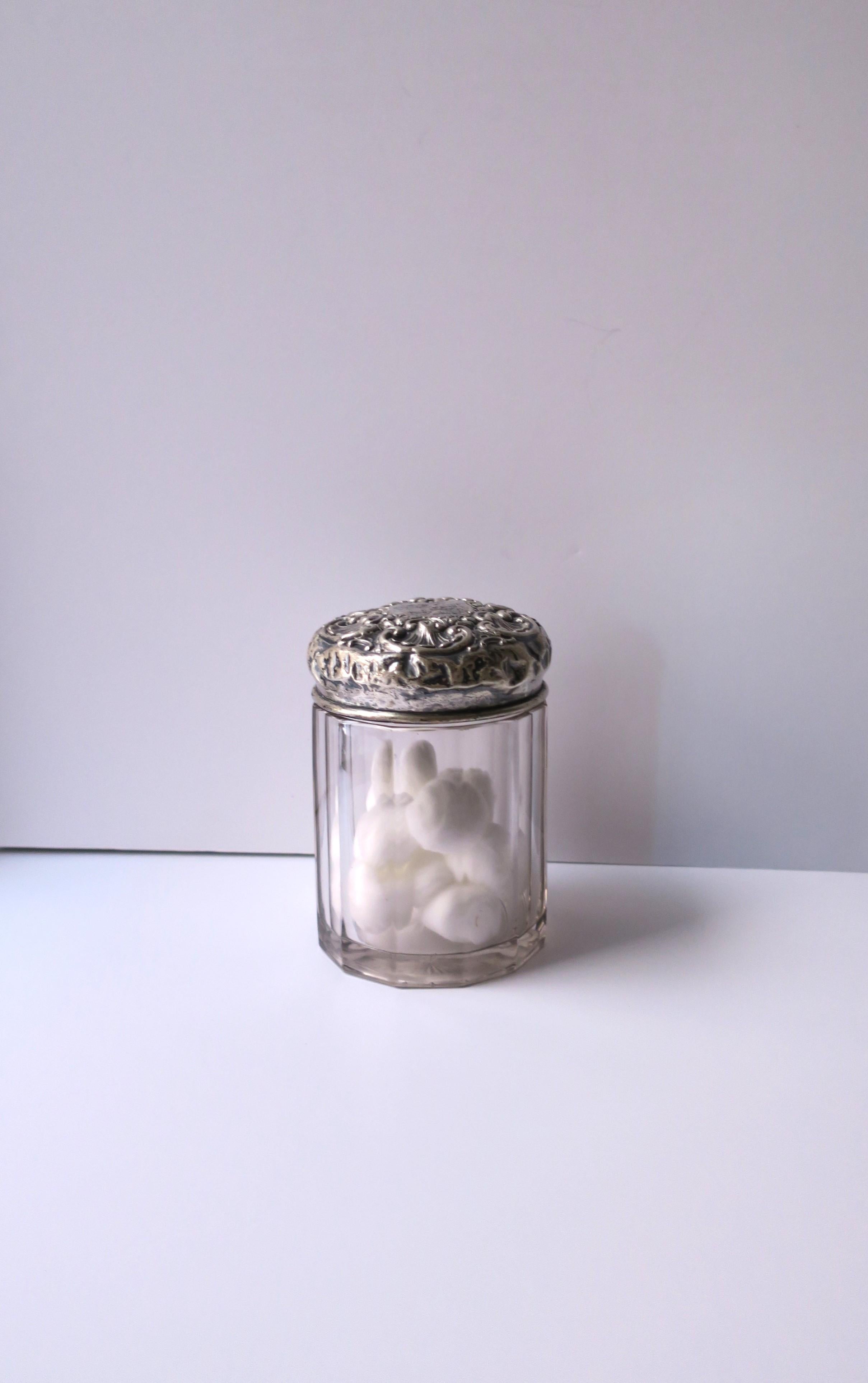 A sterling silver and crystal vanity or dresser jar, Victorian period, circa late 19th century. The sterling top/lid has a repose floral design around, a center monogram, a paneled shape body, and a cut starburst bottom. A great piece for a vanity