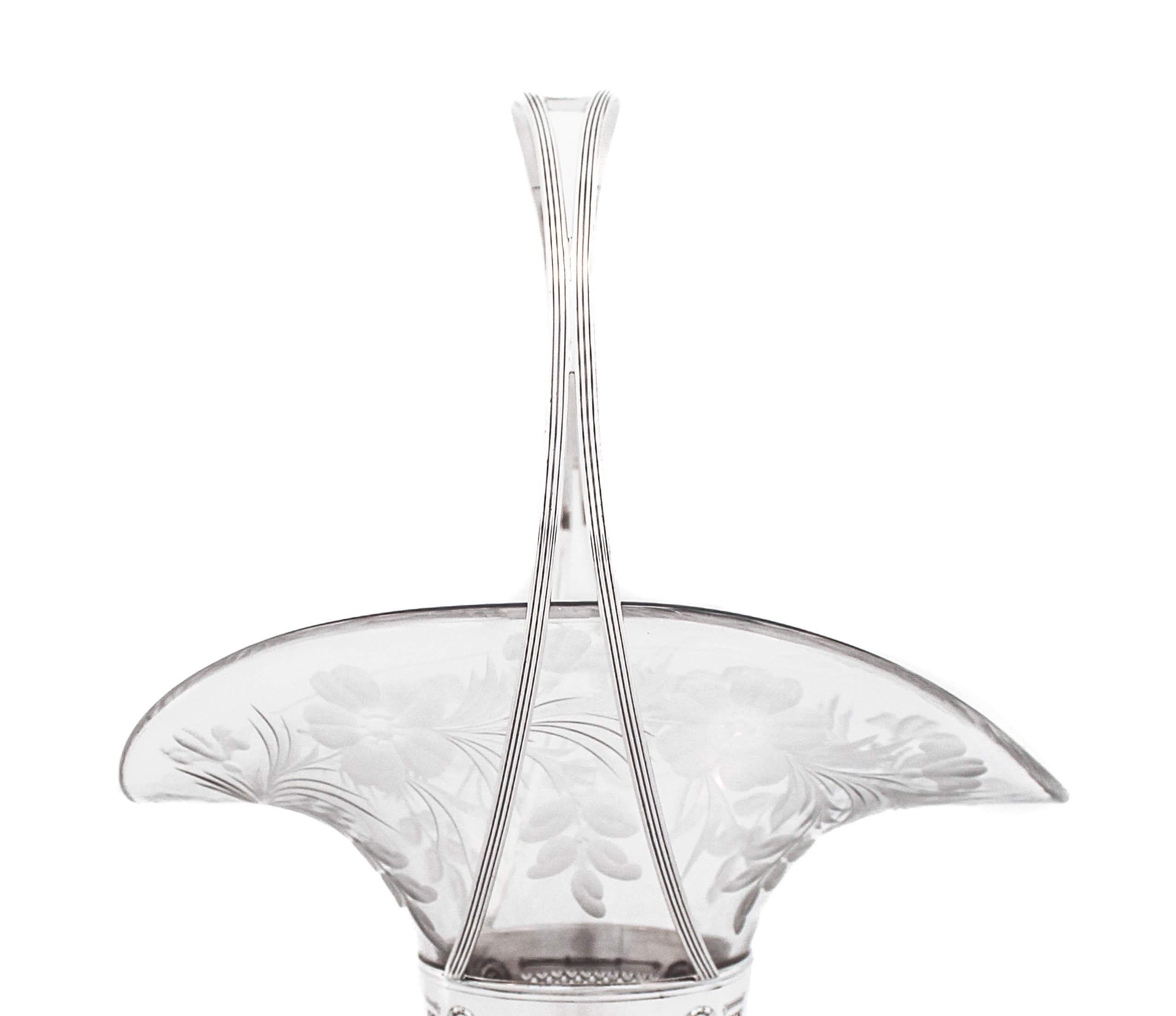 Nous vous proposons un vase en argent sterling avec anse (panier) fabriqué par Dominick and Haff de New York.  Il est doté d'une doublure en verre d'origine de forme ovale avec un motif floral gravé à l'acide.  La partie supérieure de l'argent est