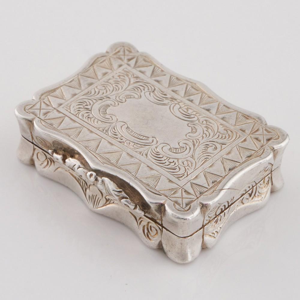 Heading : Sterling silver vinaigrette
Date : Hallmarked in Birmingham in 1860 for Alfred Taylor
Period : Victoria
Origin : Birmingham, England
Decoration : Tooled van-dyke triangle type border surrounding a scrolled cartouche. Parcel gilt interior