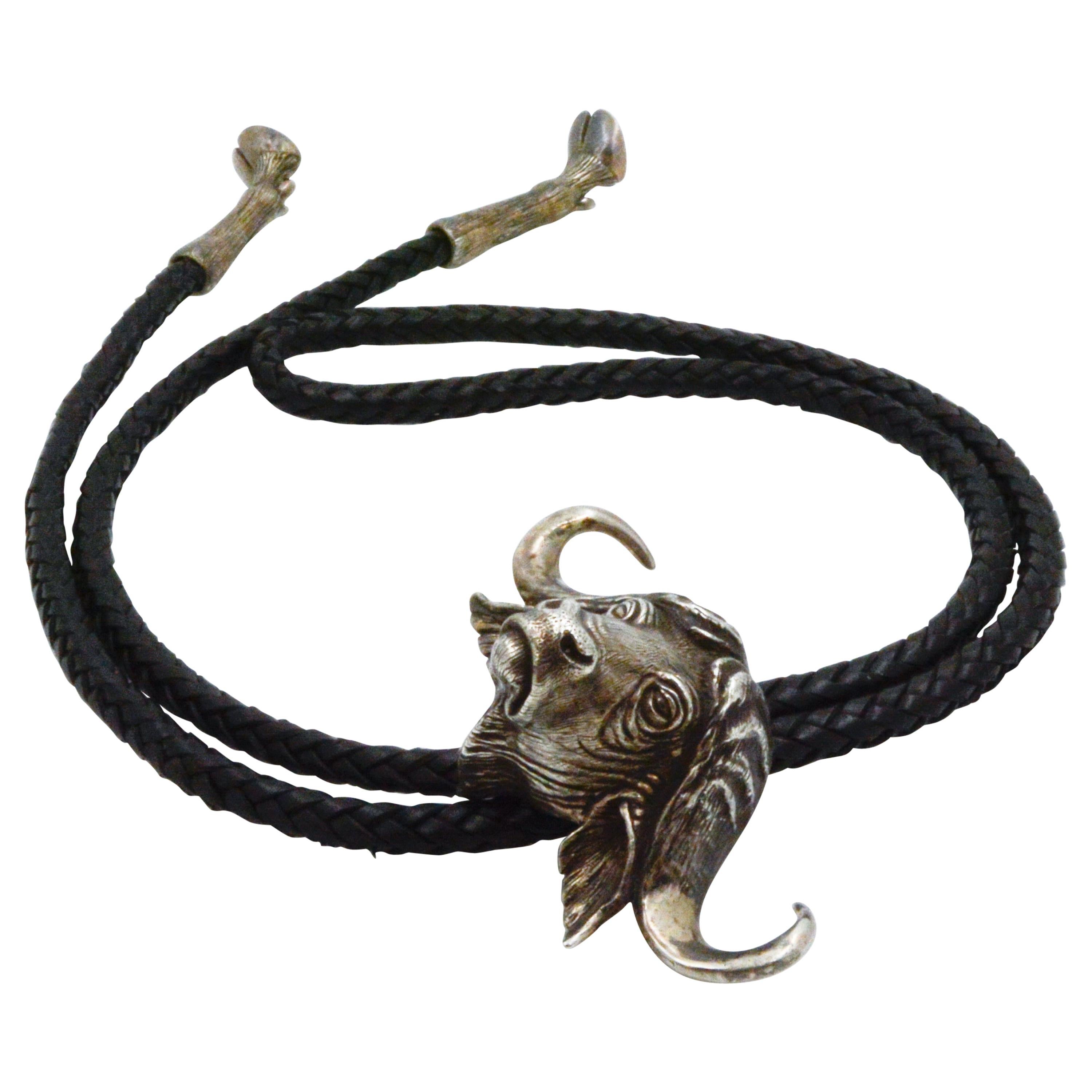 This charming sterling silver Water Buffalo bolo tie is signed by Jug. It is paired with a 40in braided black leather strap. It also has two sterling silver hooves at the tip of the pieces. 