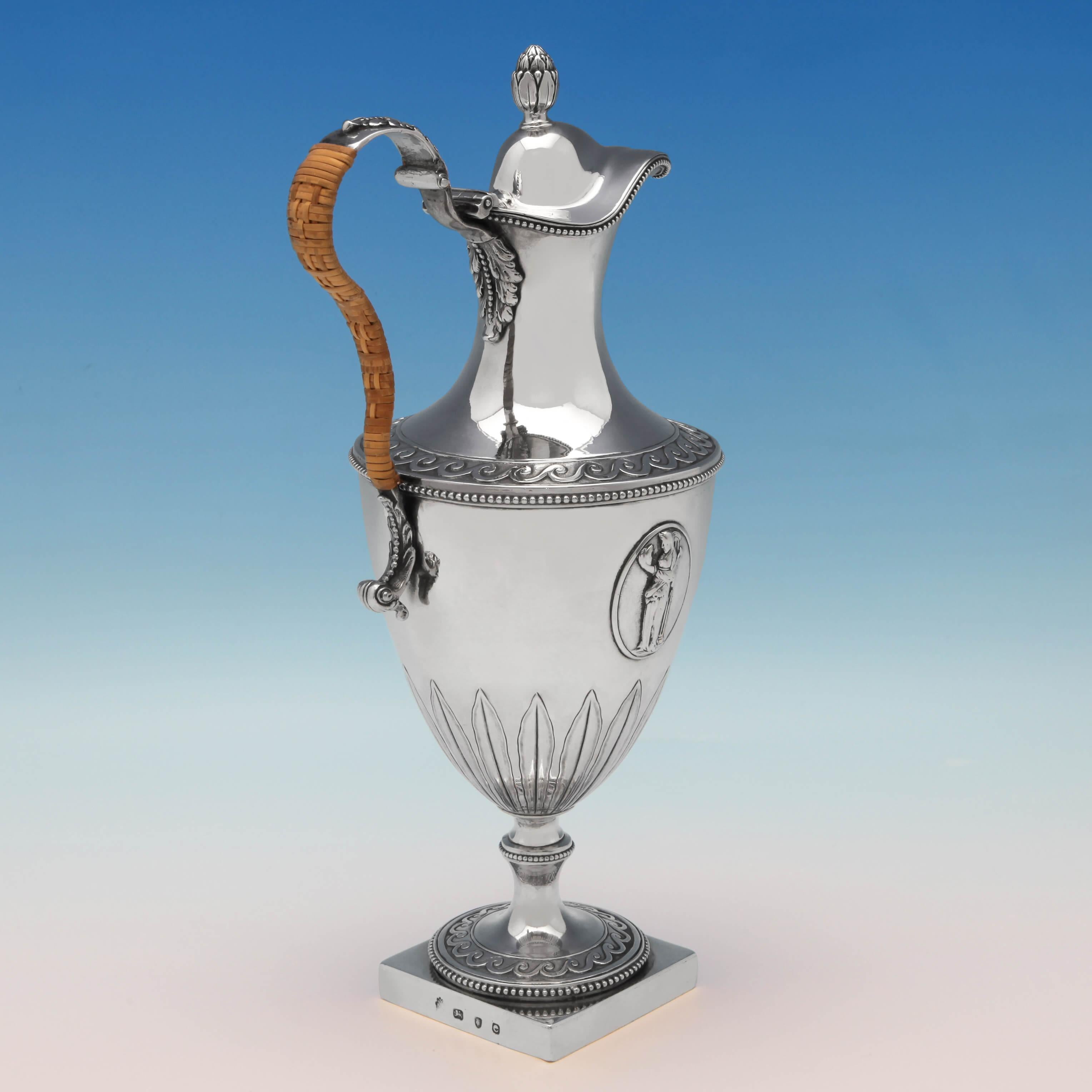 Hallmarked in London in 1780 by Fogelberg & Gilbert, this handsome, George III, antique sterling silver wine ewer or water jug, features neoclassical decoration, bead borders and a wicker handle. The wine jug measures 12